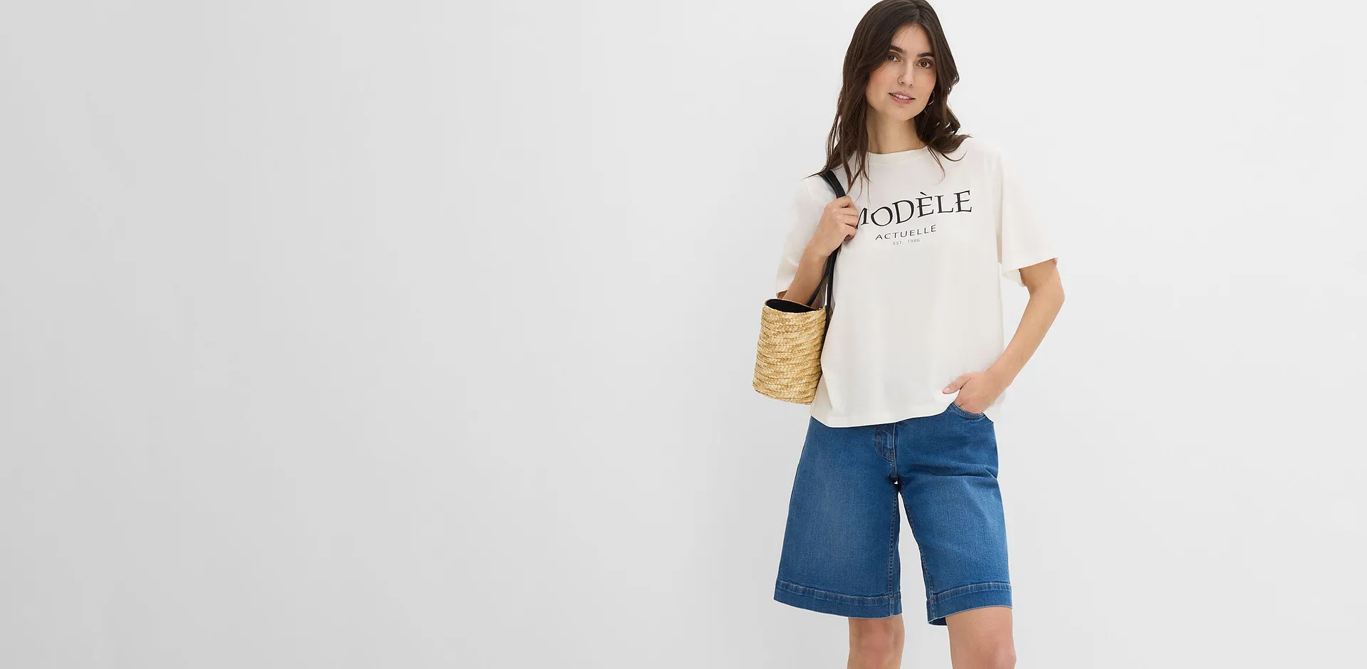 Femme v&ecirc;tue d'un t-shirt blanc d&eacute;contract&eacute; avec une inscription et d'un bermuda en jean bleu de coupe large.