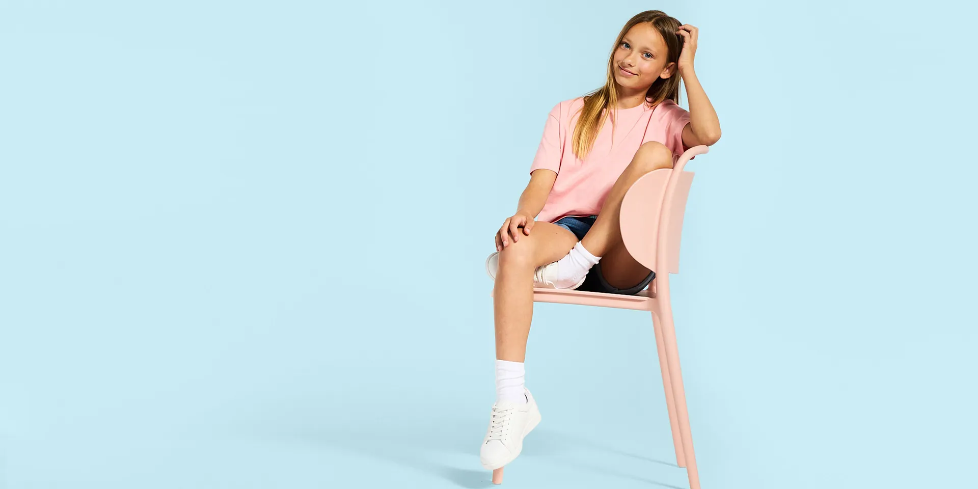 T-shirt rose, short en jean, chaussettes et tennis blanches.