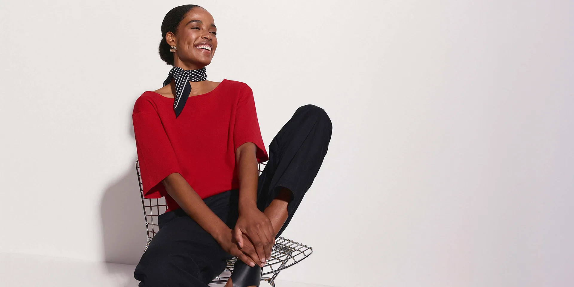Une femme v&ecirc;tue d'un T-shirt rouge, pantalon noir et un foulard chic &agrave; pois autour du cou.