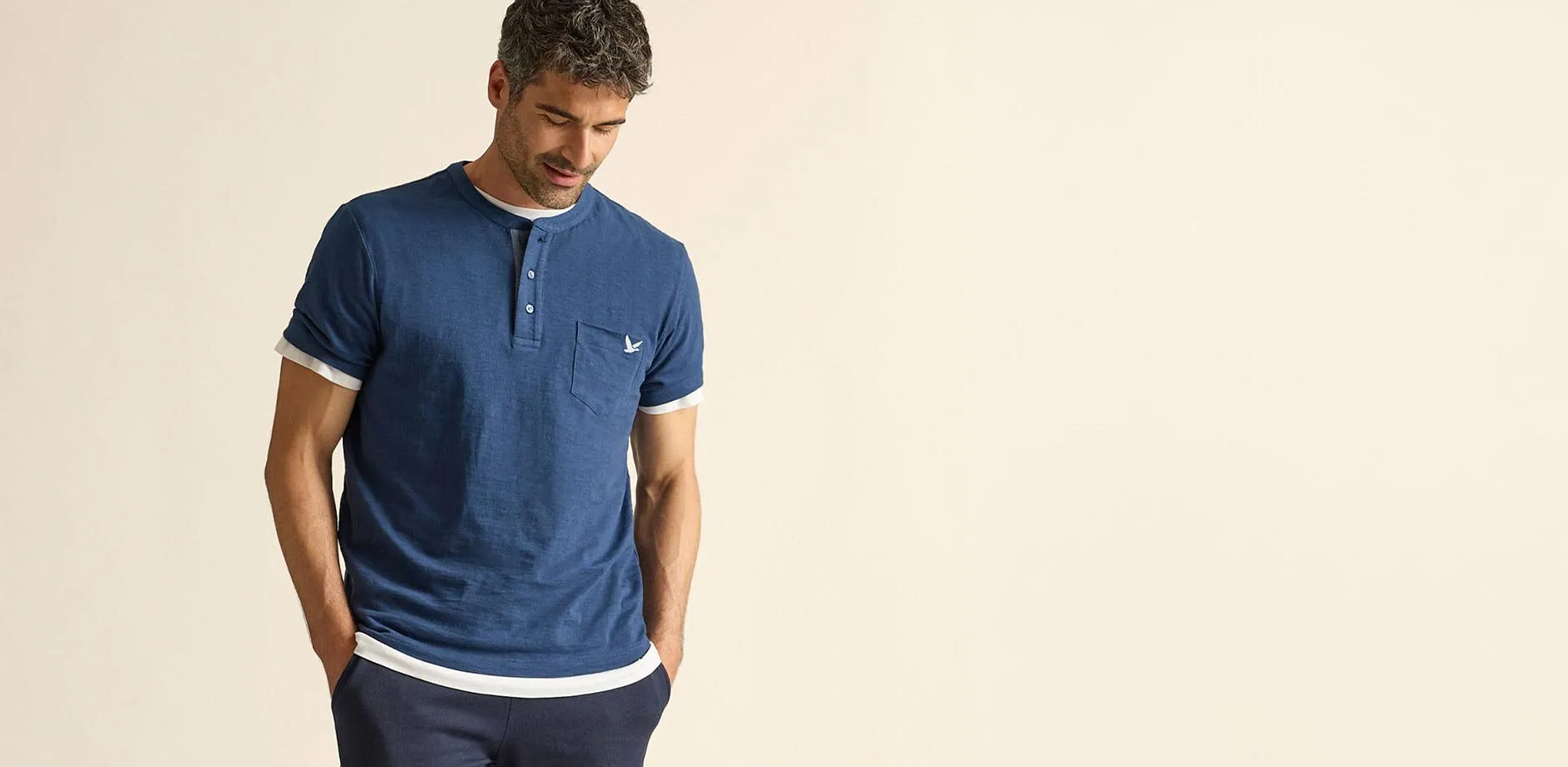 T-shirt bleu d&eacute;contract&eacute; &agrave; col tunisien avec des touches de blanc, par dessus un T-shirt blanc et pantalon fonc&eacute;.