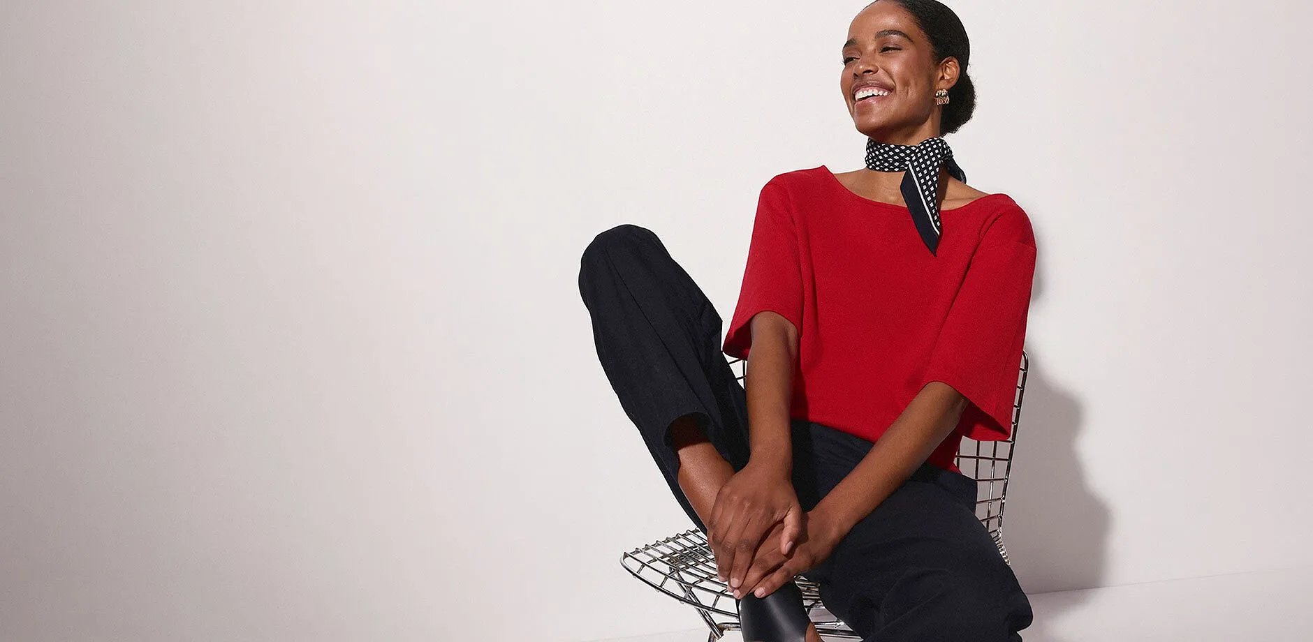 Une femme v&ecirc;tue d'un T-shirt rouge, pantalon noir et un foulard chic &agrave; pois autour du cou.