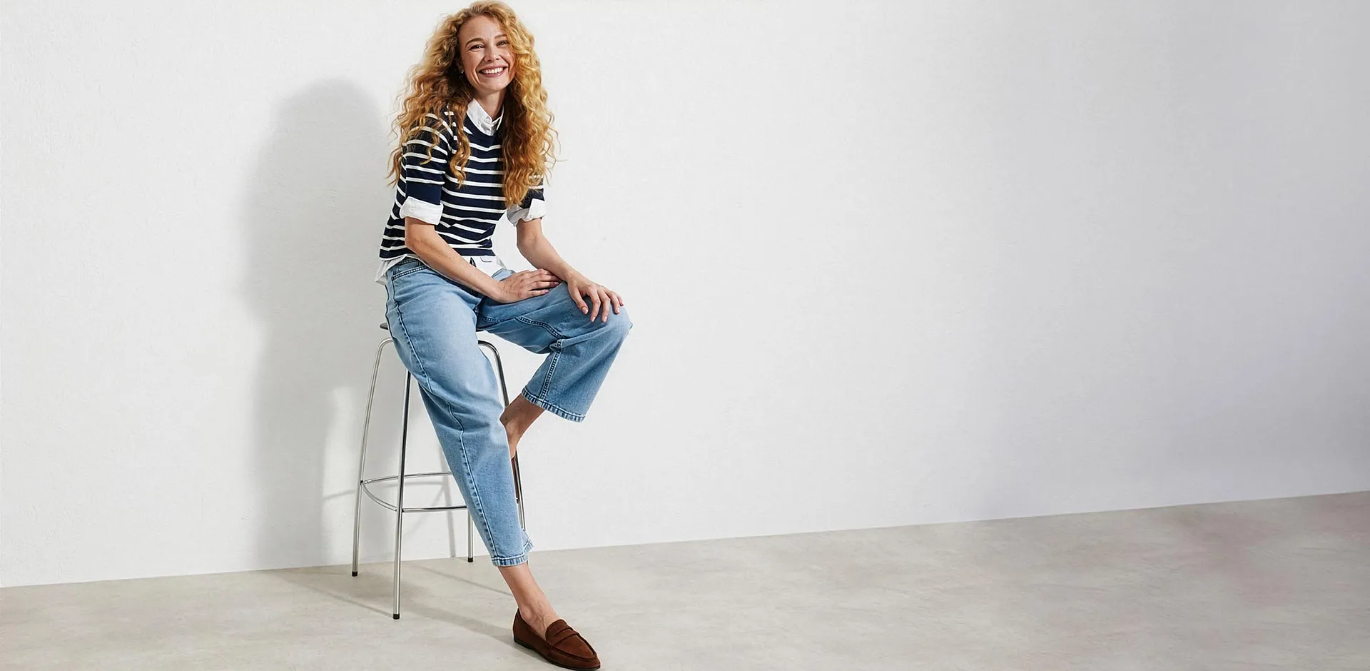 Pull &agrave; rayures sur un chemisier, jean bleu clair et mocassins marron.