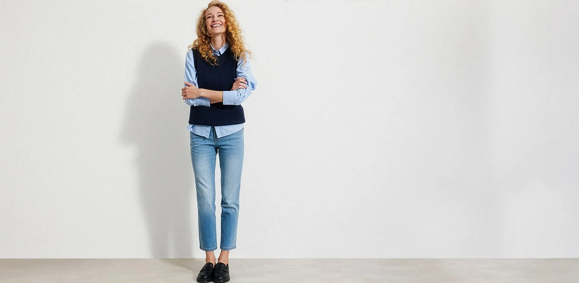 Chemise bleu clair, gilet sans manches bleu fonc&eacute;, jean bleu et mocassins noirs.