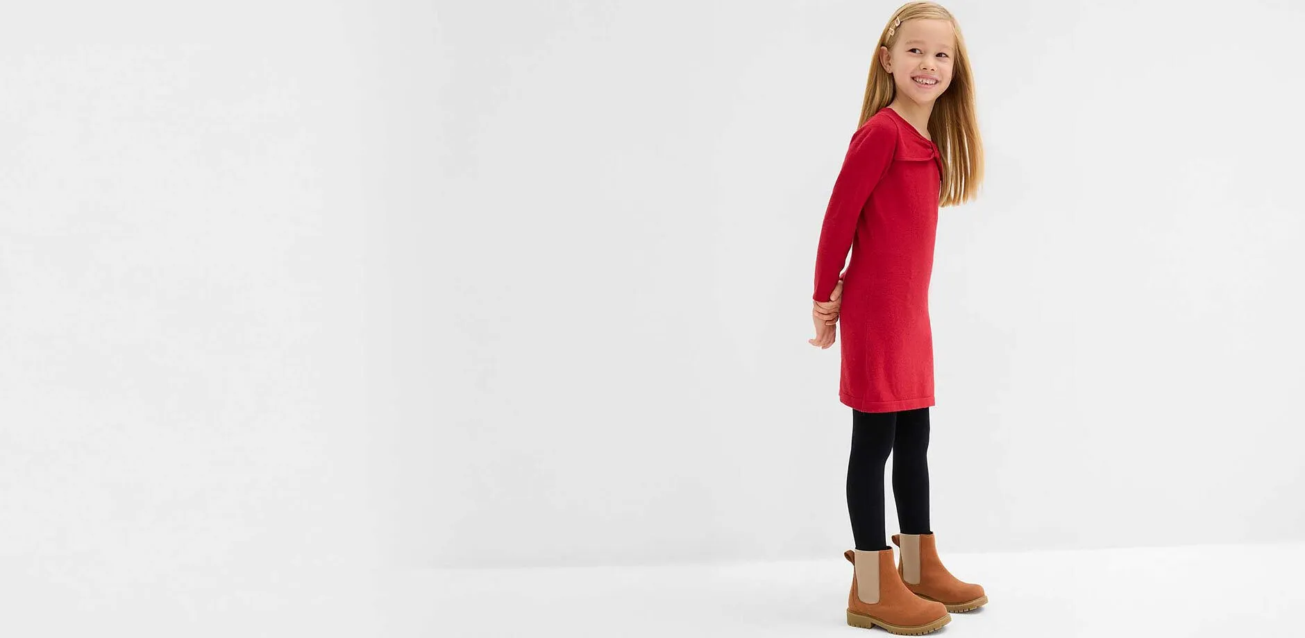 Petite fille v&ecirc;tue d'une robe en maille rouge.