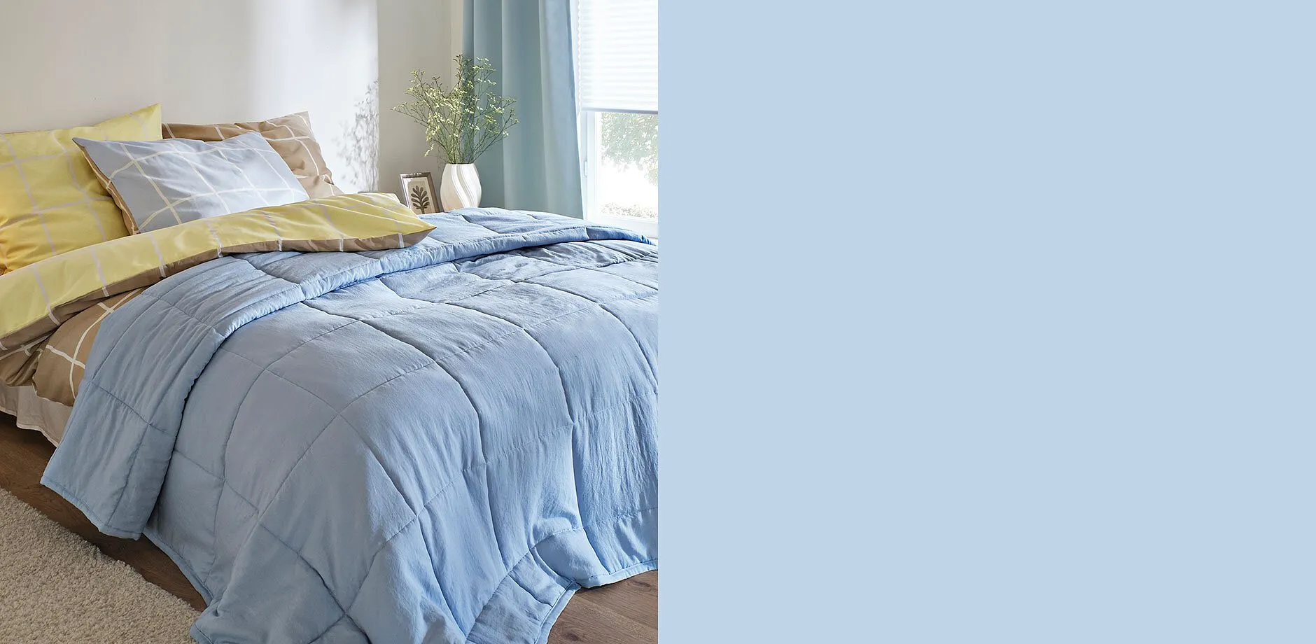 Chambre &agrave; coucher avec dessus de lit bleu clair, couette et coussins jaunes.