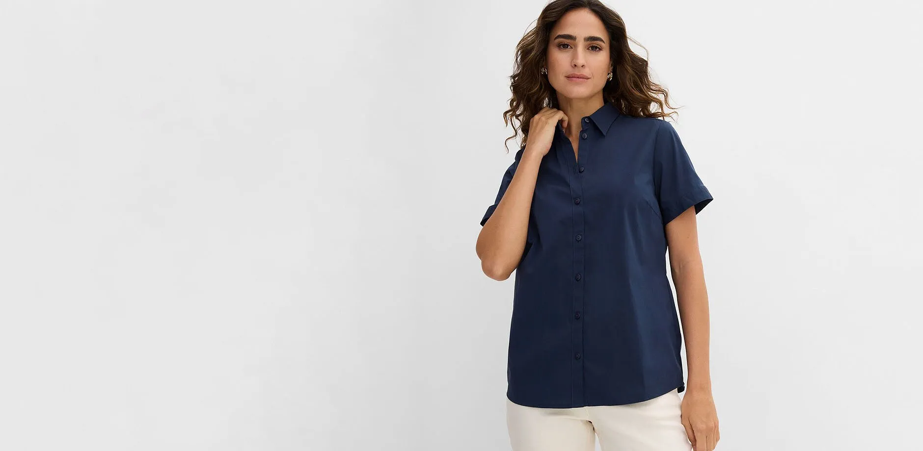 Chemisier bleu fonc&eacute; &agrave; manches courtes et petit col, associ&eacute; &agrave; un pantalon clair.