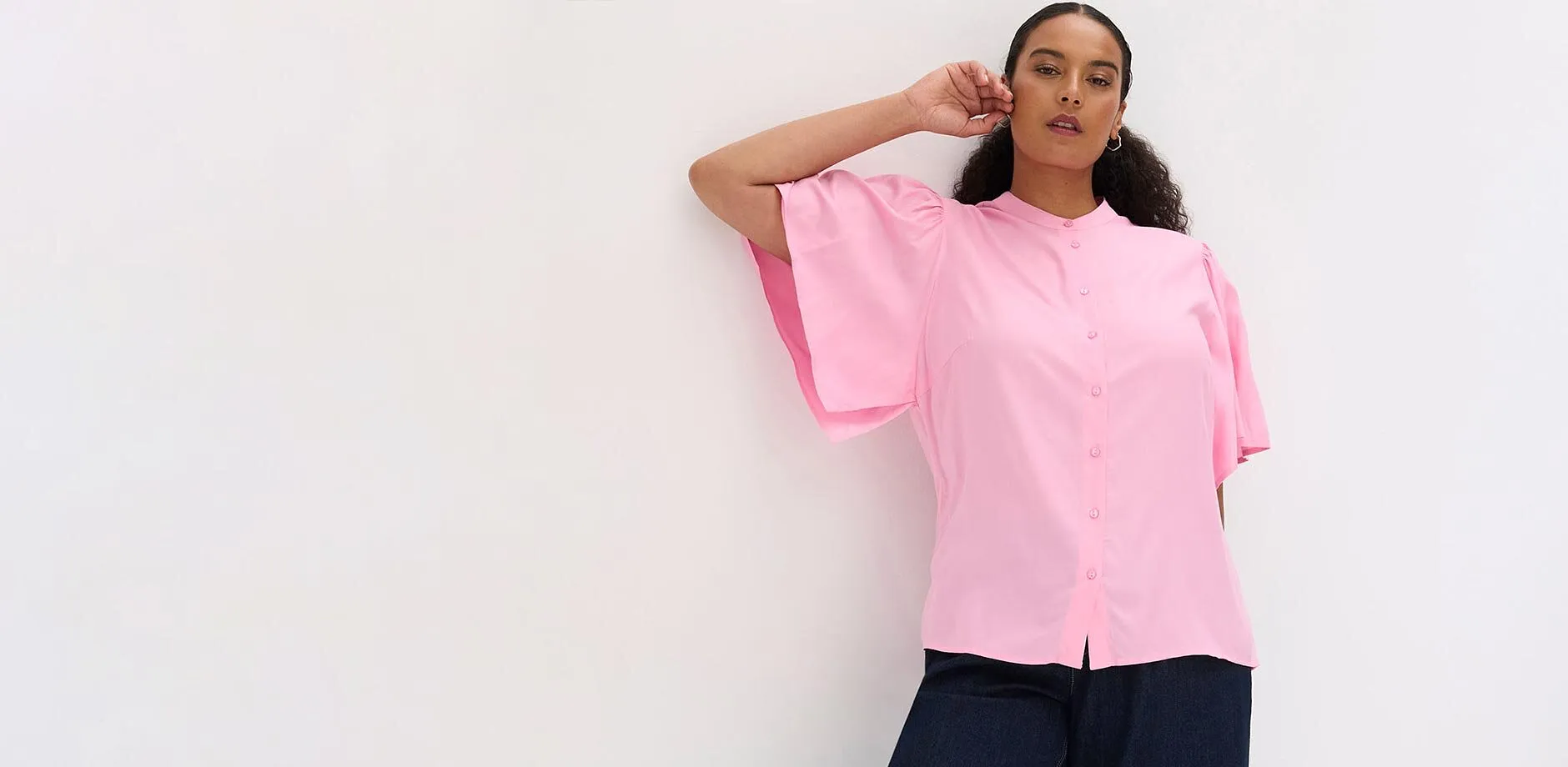 Blouse rose &agrave; manches larges, col montant et patte de boutonnage.