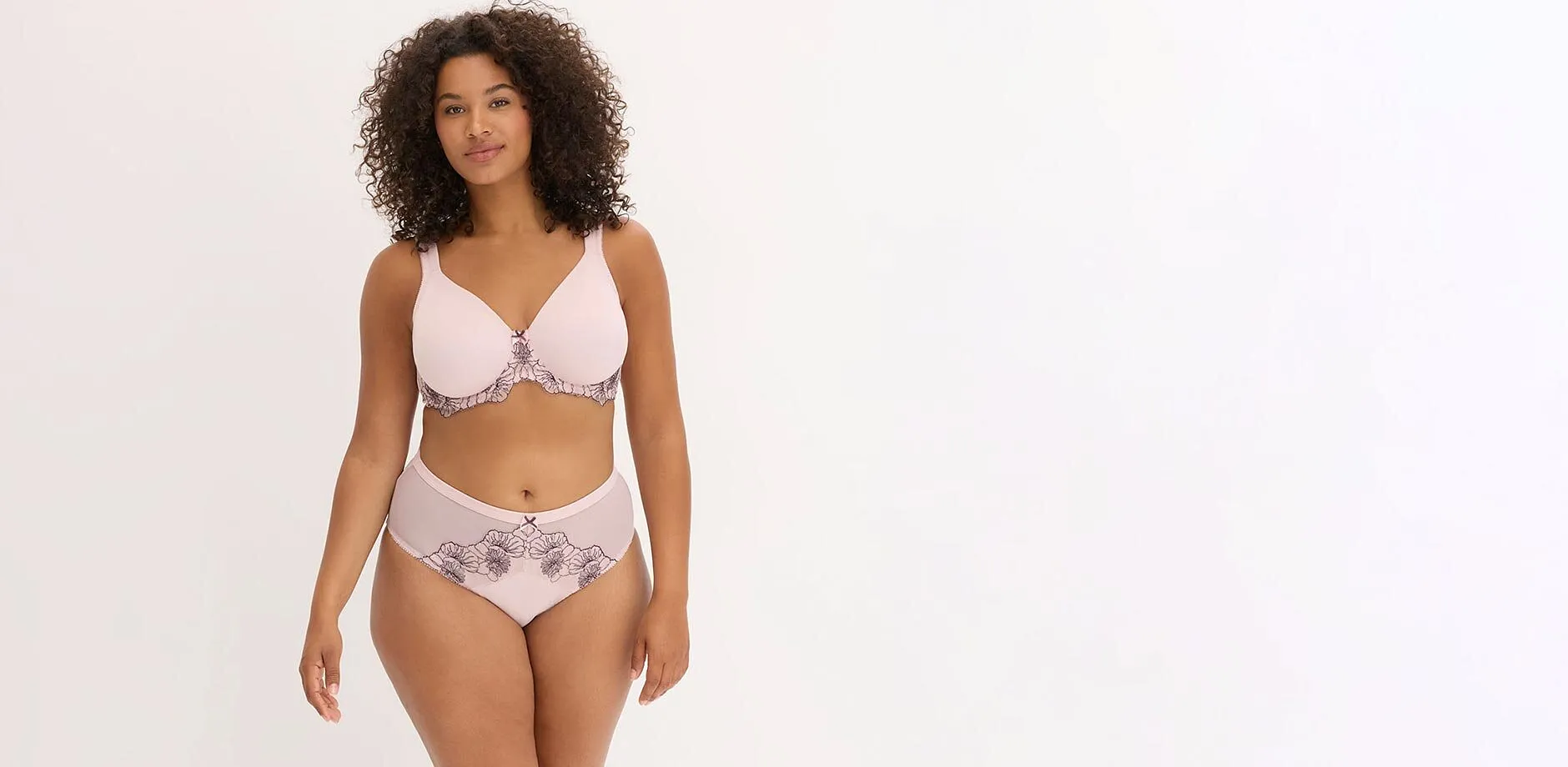 Ensemble de lingerie rose clair avec une broderie florale noire raffin&eacute;e sur le soutien-gorge et le slip.
