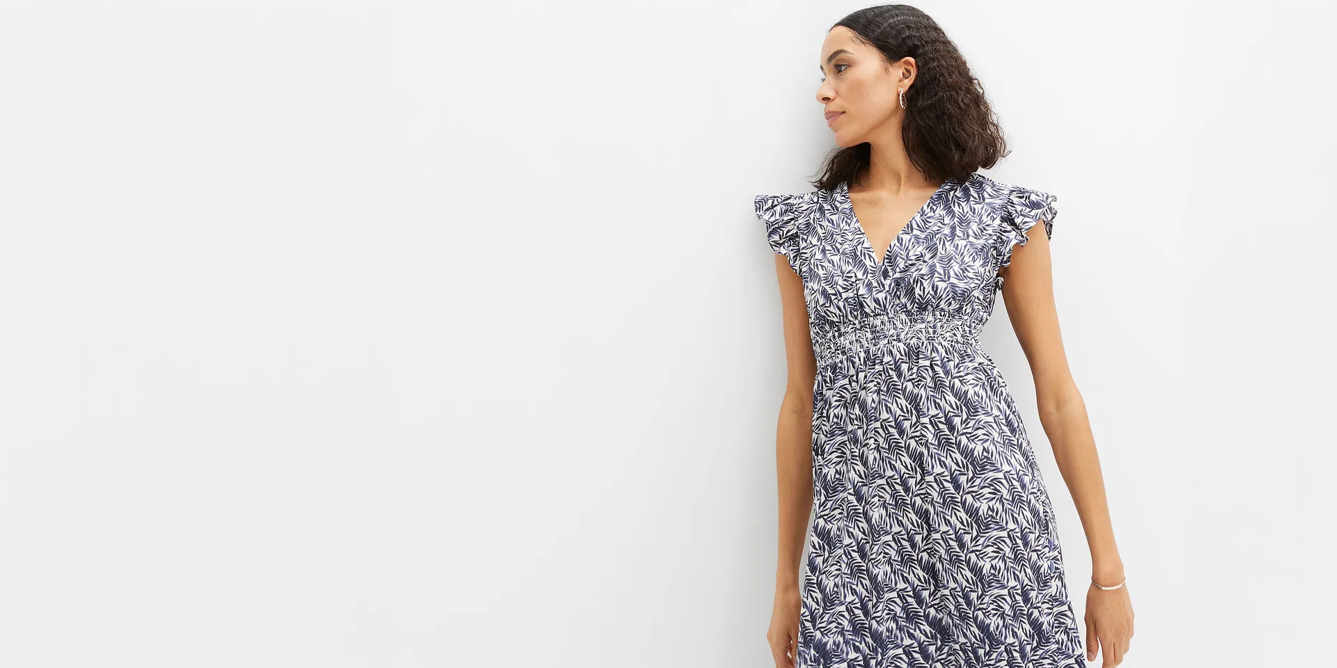 Elegantes Sommerkleid mit blauem Bl&auml;ttermuster, V-Ausschnitt und geraffter Taille.