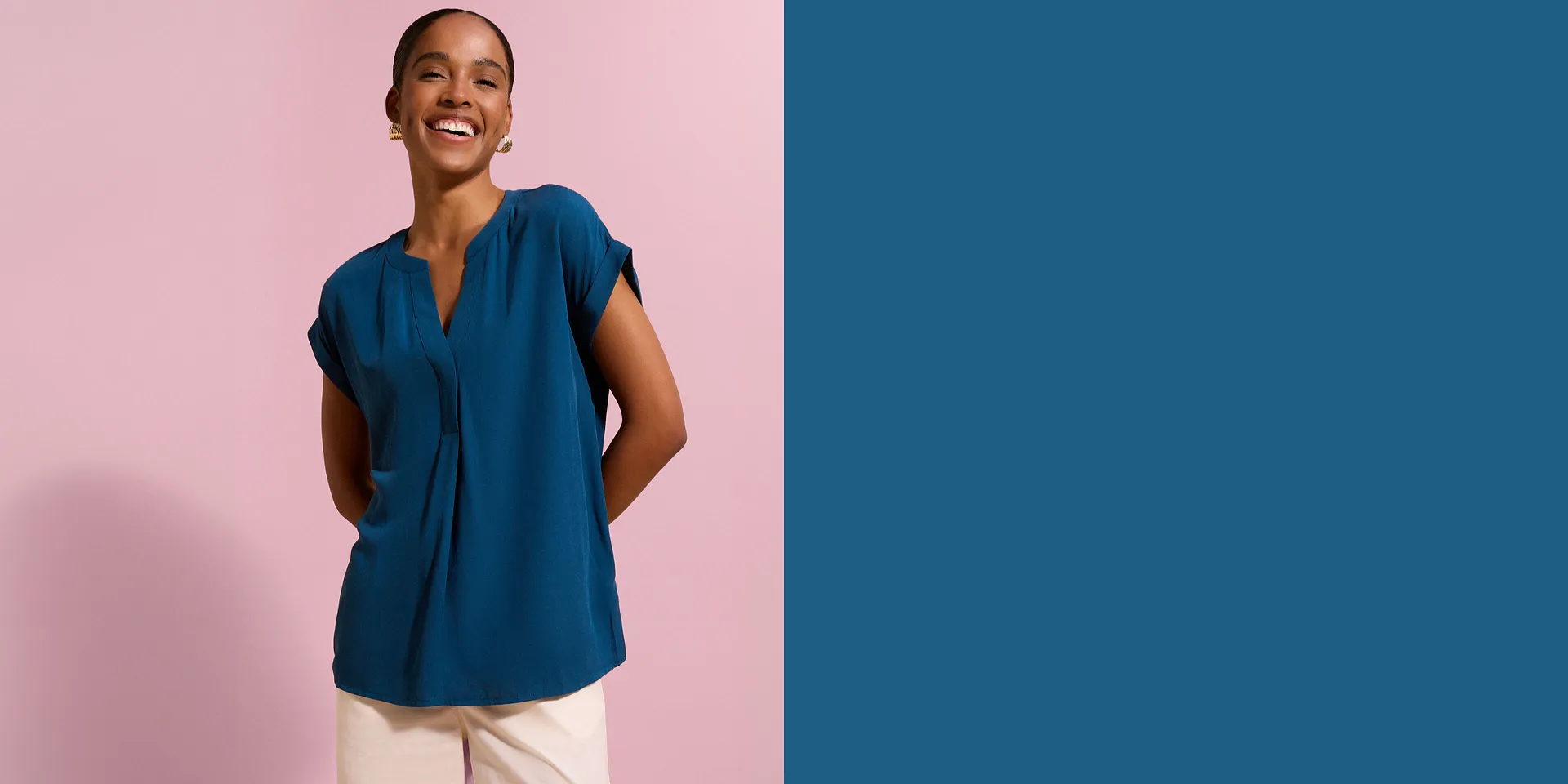 Modische tealfarbene Bluse mit V-Ausschnitt und hochgekrempelten &Auml;rmeln, kombiniert mit heller Hose.