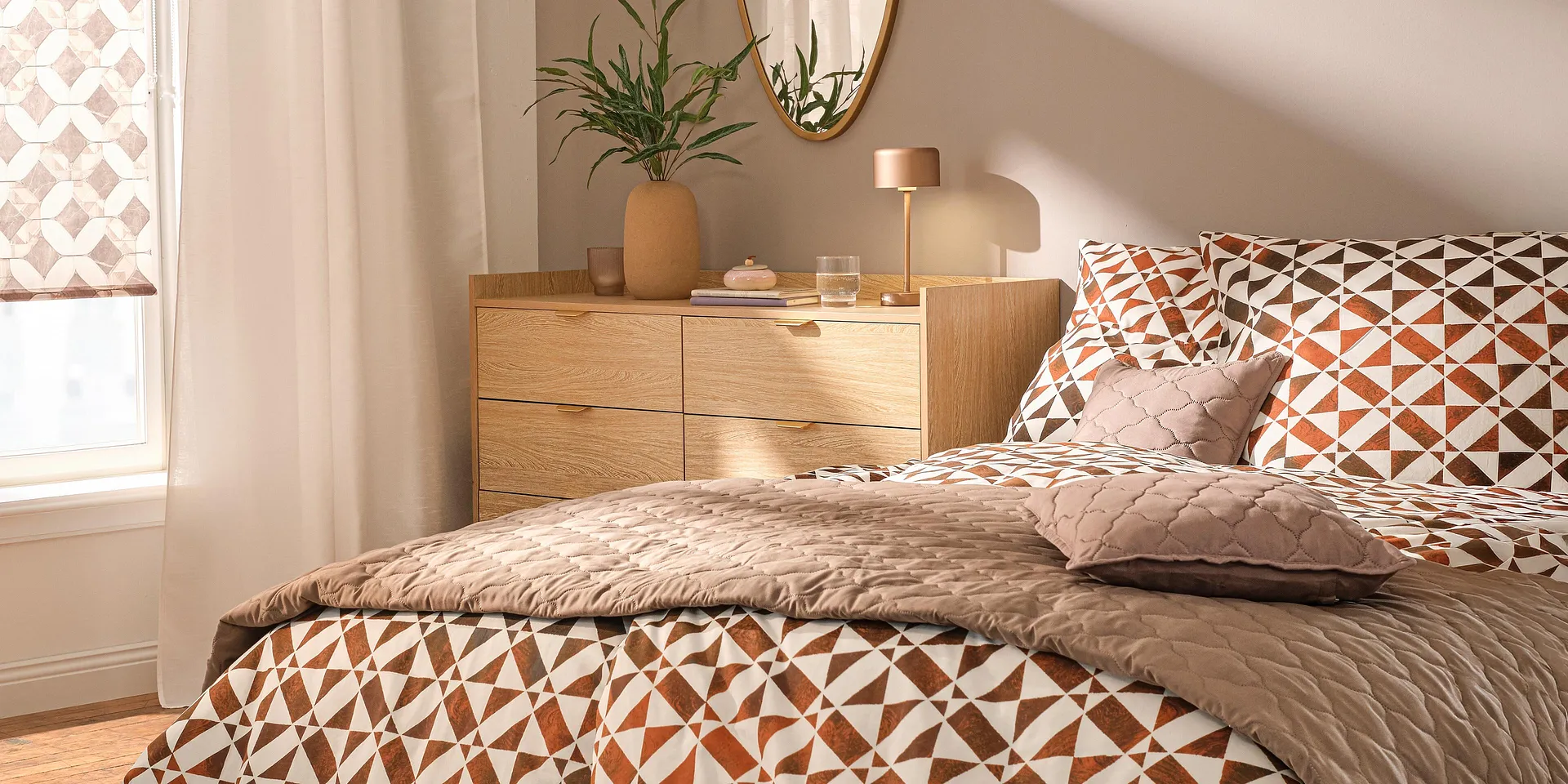 Gemusterte Bettw&auml;sche in Braun- und Oranget&ouml;nen, dazu Steppdecke und Zierkissen.