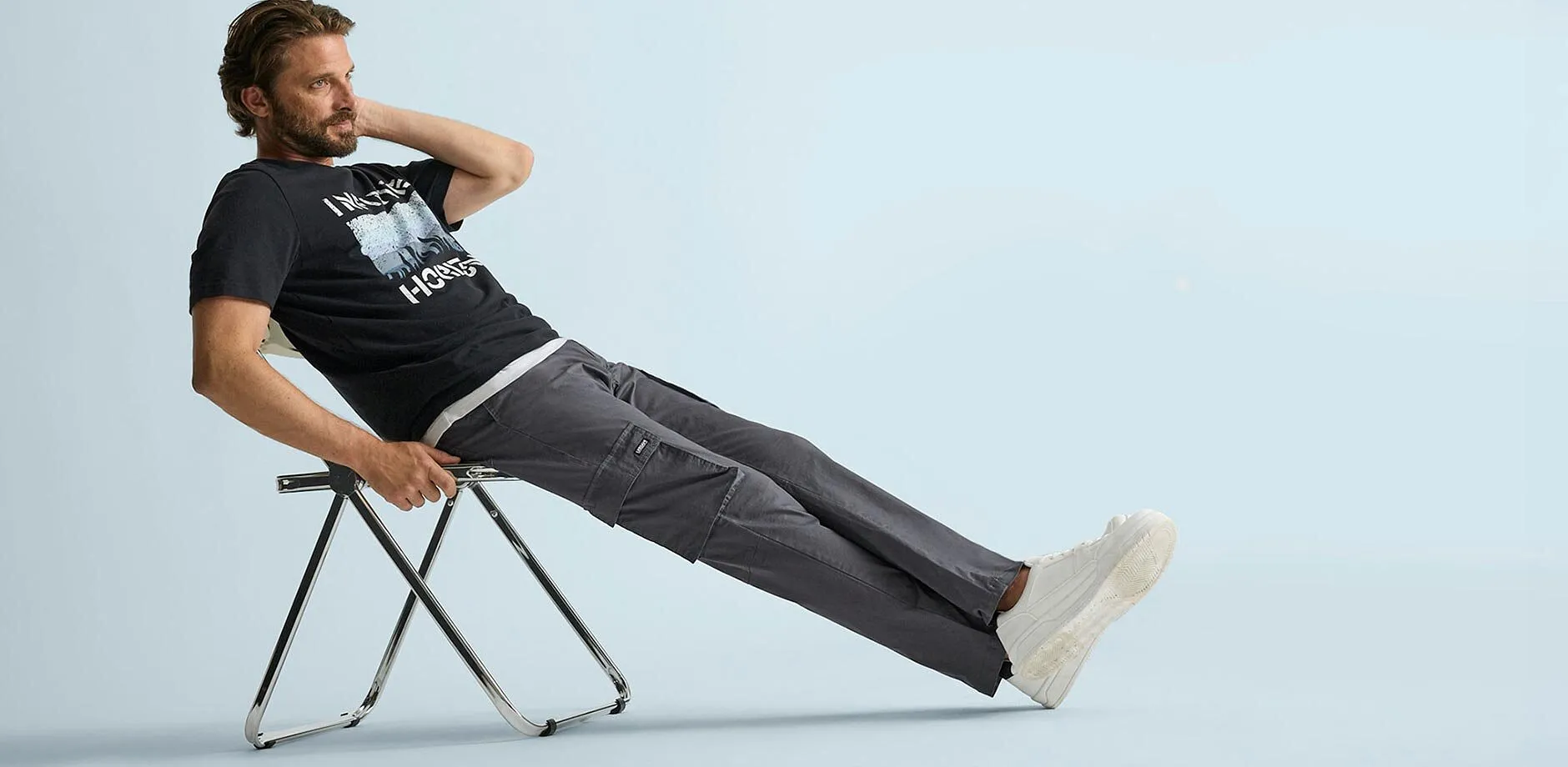 Schwarzes T-Shirt mit Aufdruck, bequeme graue Cargohose und l&auml;ssige wei&szlig;e Sneaker.