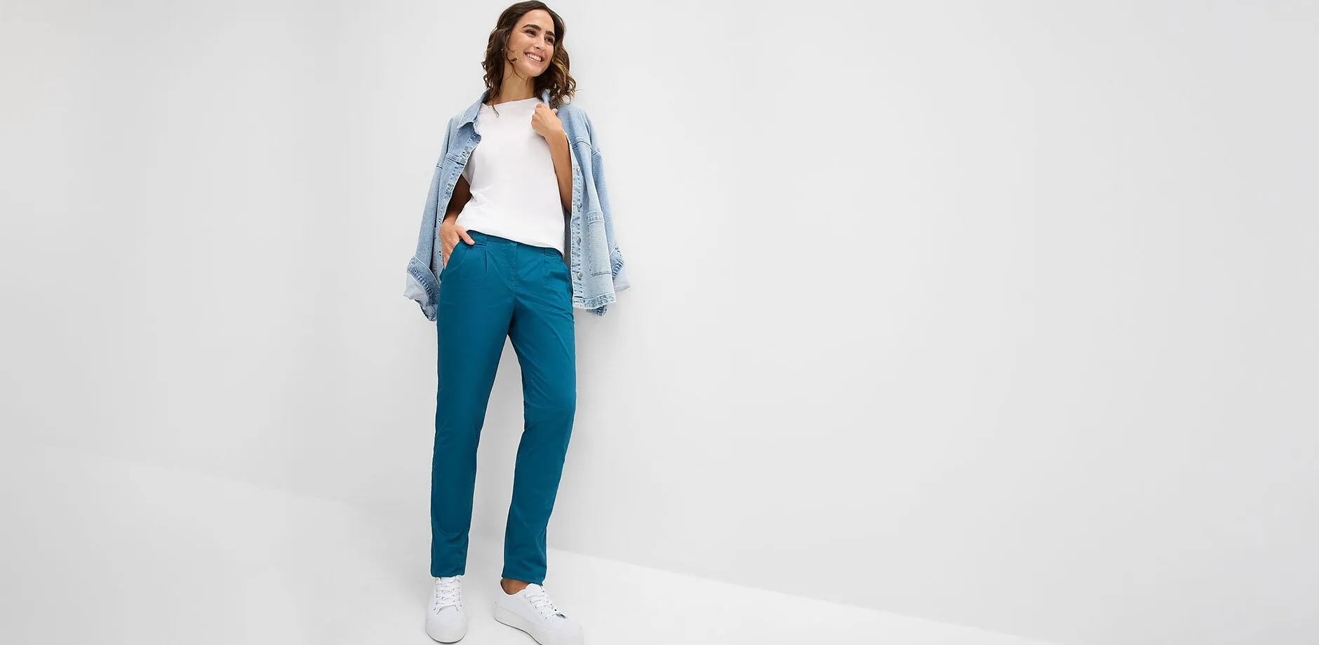 Pantalon turquoise, T-shirt blanc, veste en jean d&eacute;contract&eacute;e et baskets blanches.