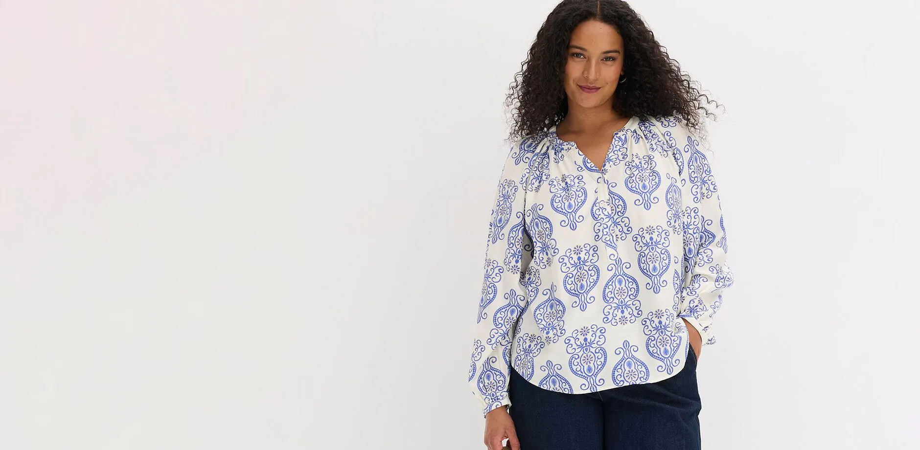 Blouse &agrave; manches longues blanche imprim&eacute;e avec des motifs bleus fantaisie et pantalon fonc&eacute;.