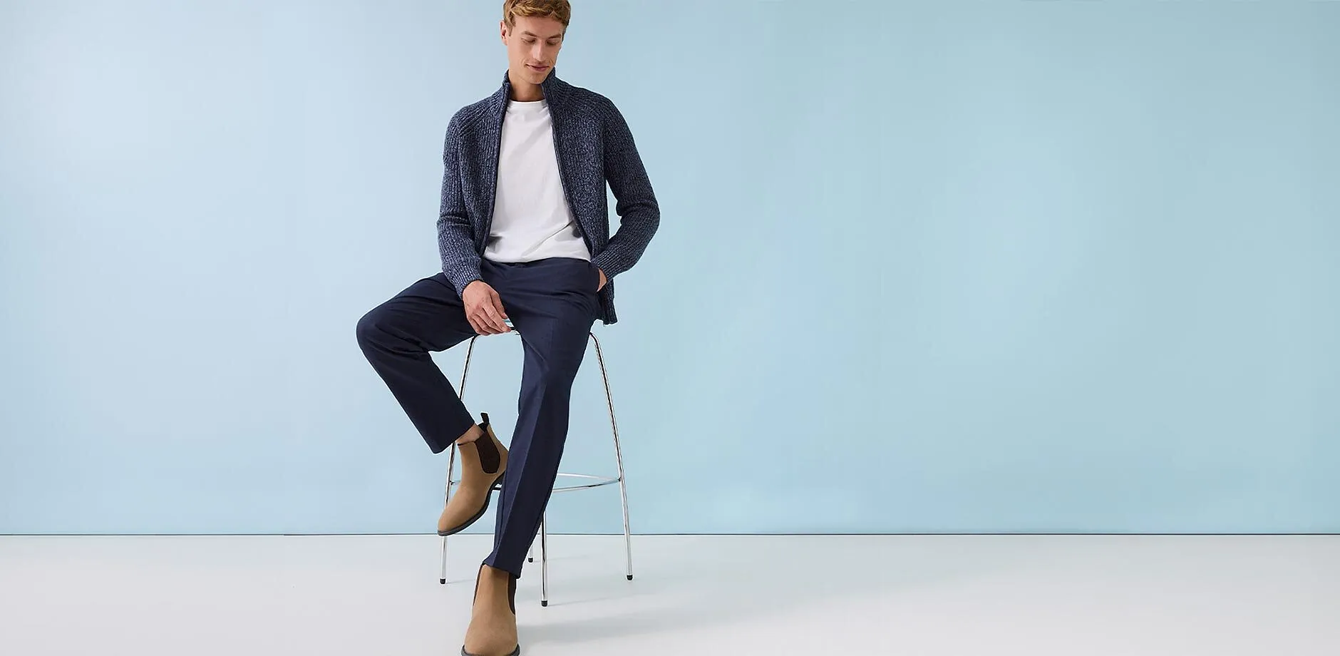 Dunkelblaue Strickjacke &uuml;ber wei&szlig;em T-Shirt, dazu elegante Hose und beige Wildleder-Boots.