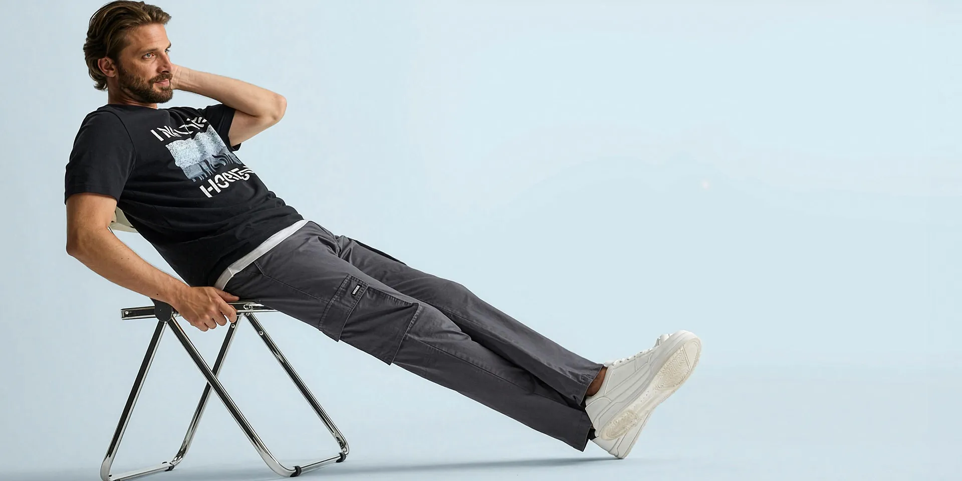 T-shirt noir &agrave; imprim&eacute;, pantalon cargo gris confortable et sneakers blanches d&eacute;contract&eacute;es.