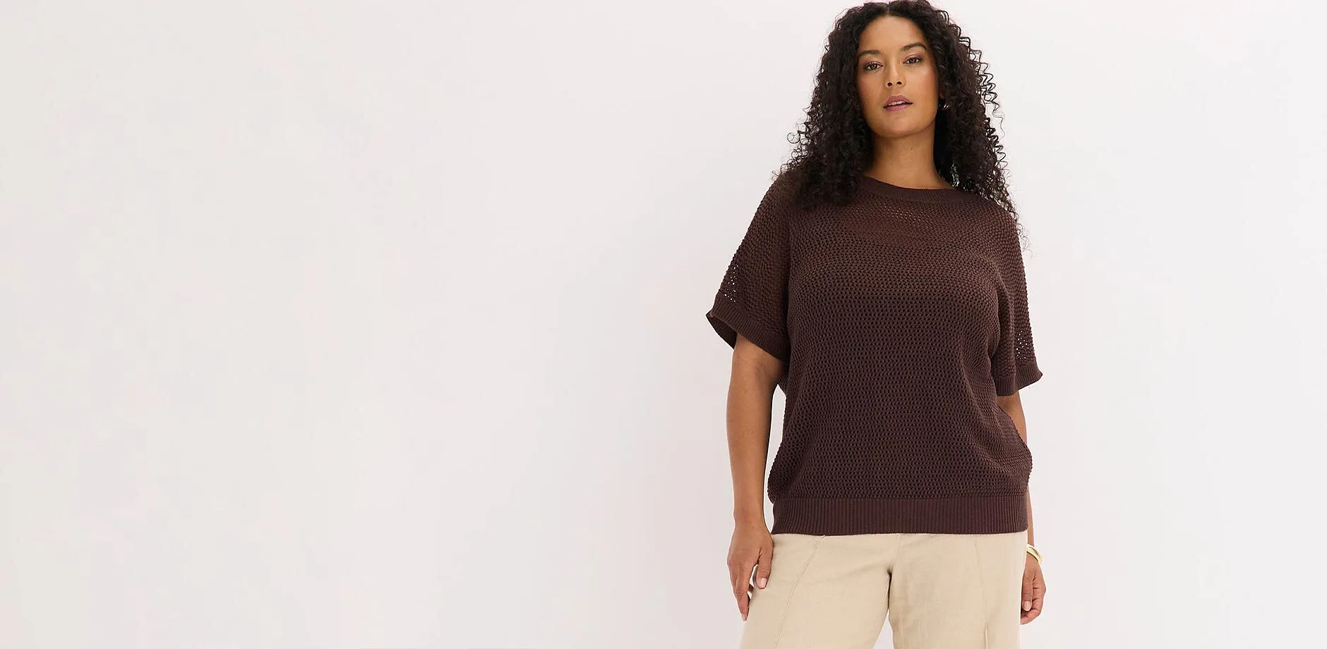 Pull oversize marron et pantalon beige.