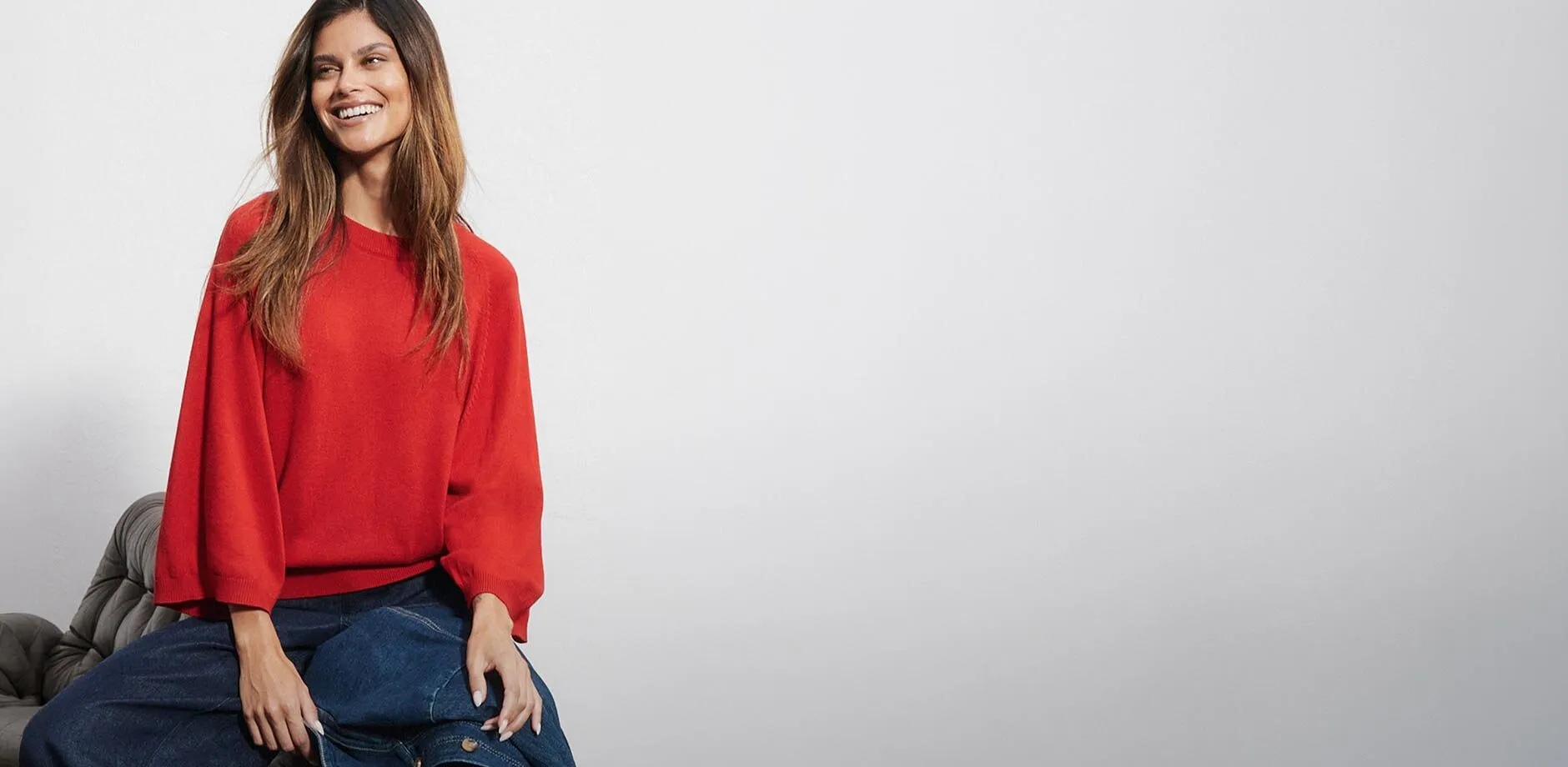 Pull rouge &agrave; manches larges, jean bleu et veste en jean.