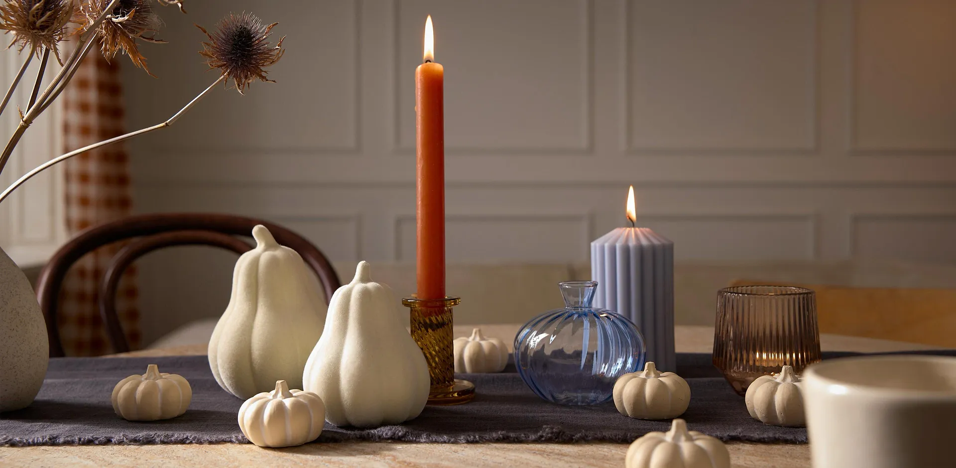 Herbstliche Dekoration mit wei&szlig;en K&uuml;rbissen und einer Kerze.