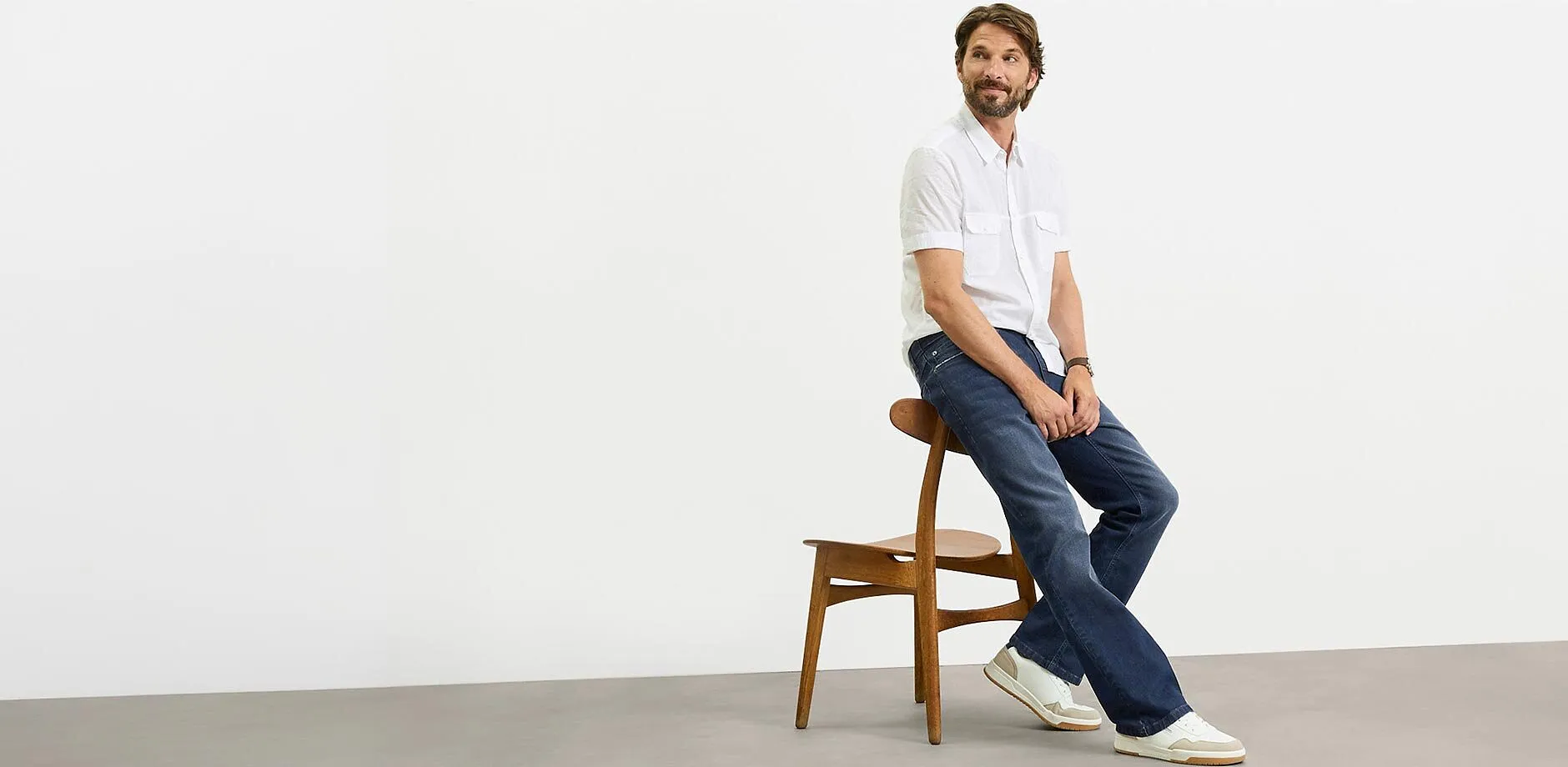 Chemise manches courtes blanche, jean fonc&eacute; et baskets blanches pour un look d&eacute;contract&eacute;.