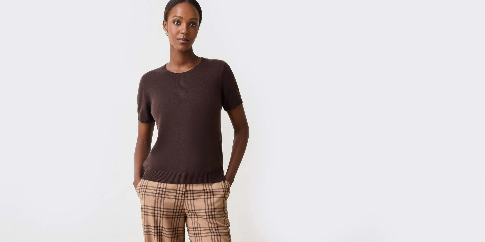 Klassisches braunes Kurzarm-Oberteil kombiniert mit einer eleganten karierten Hose.