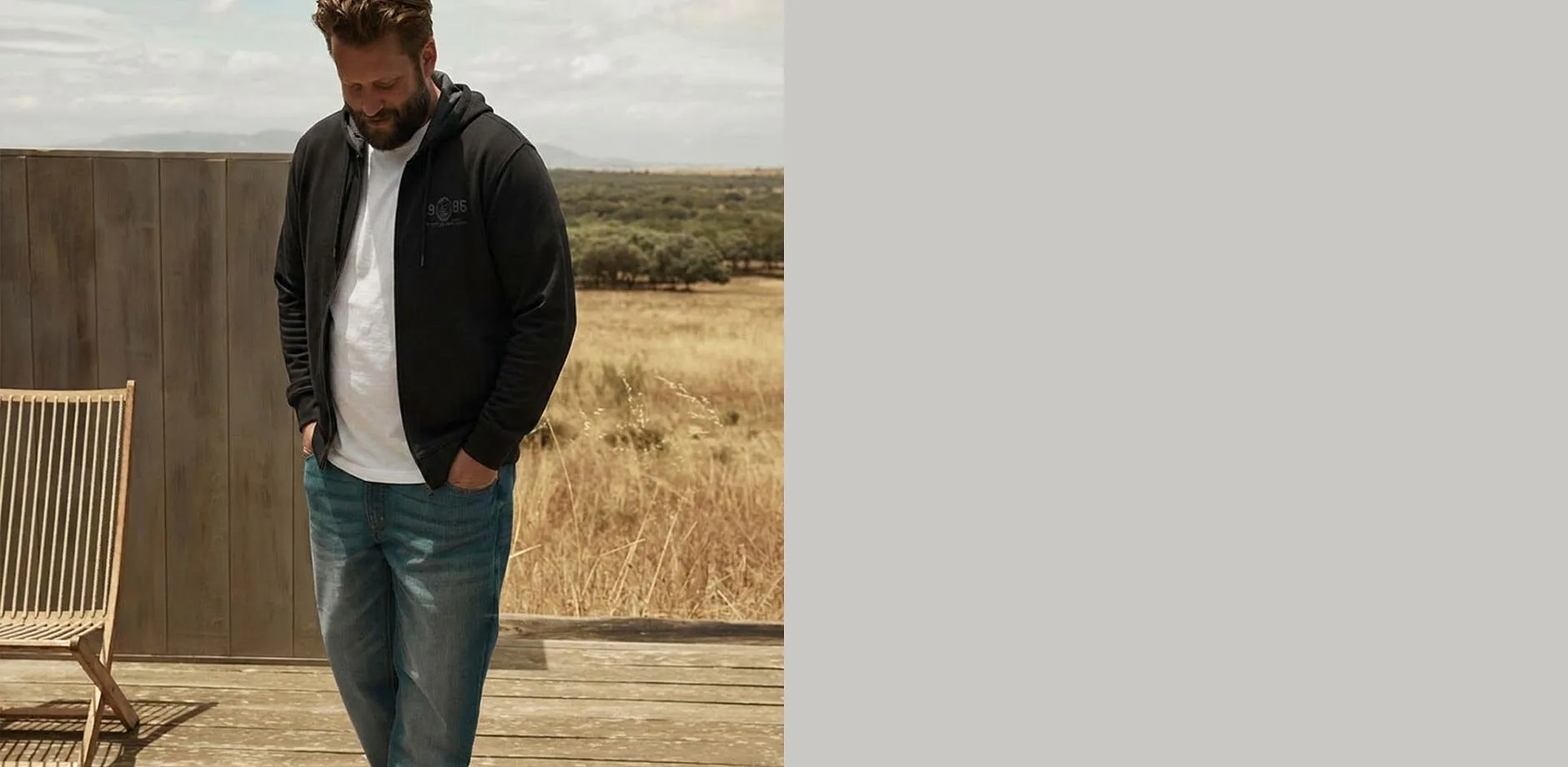 Schwarze Kapuzenjacke, wei&szlig;es T-Shirt und bequeme blaue Jeans.