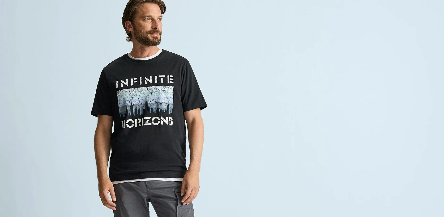 Schwarzes T-Shirt mit "Infinite Horizons" Aufdruck und l&auml;ssiger grauer Cargohose.