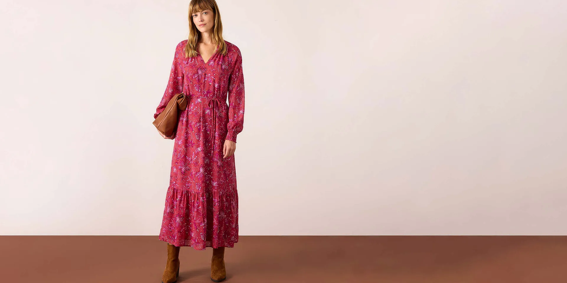 Robe longue rouge &agrave; motif floral, compl&eacute;t&eacute;e par une paire de bottes marron et un sac &agrave; main.