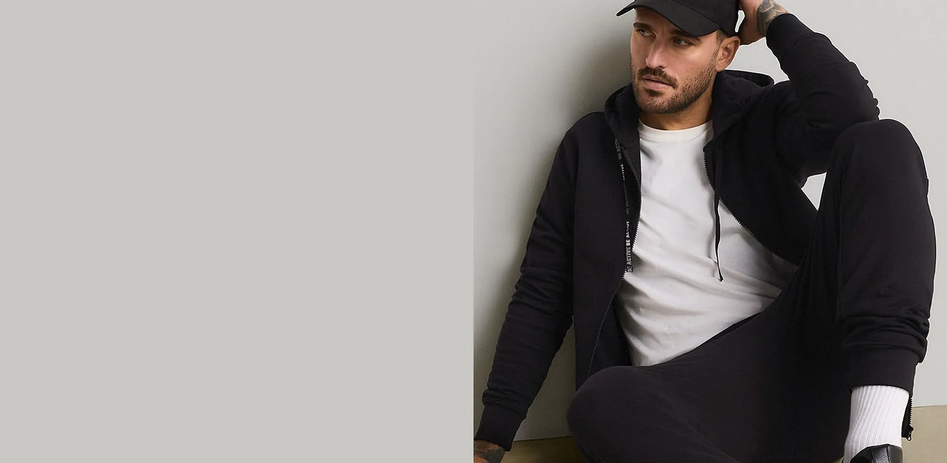 Schwarze Kappe, Hoodie, wei&szlig;es T-Shirt und schwarze Jogginghose bilden einen l&auml;ssigen Look.