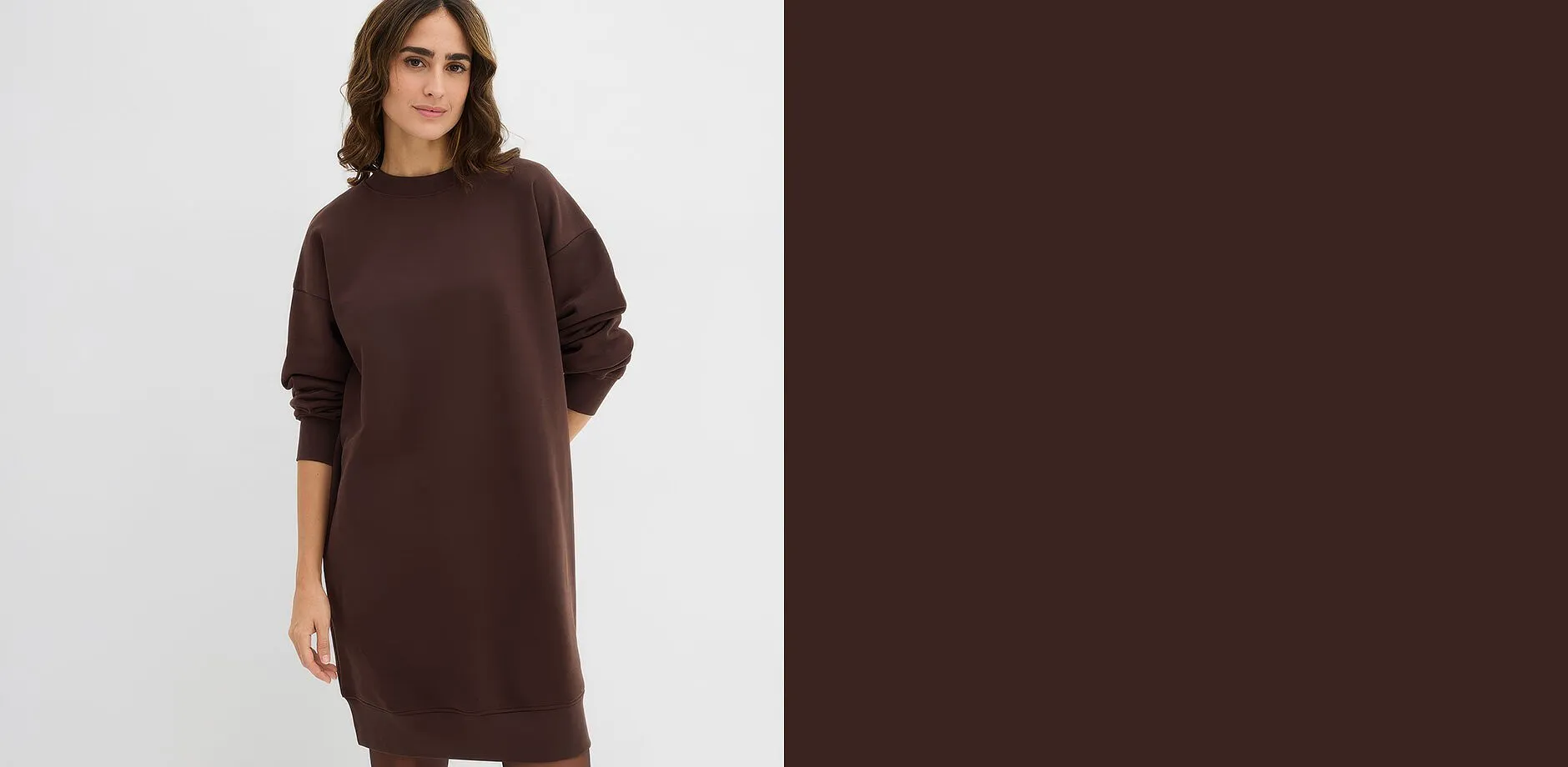Une femme v&ecirc;tue d'une longue robe en sweat marron fonc&eacute; de coupe ample.