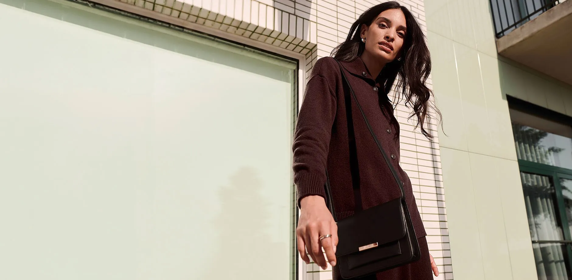 Cardigan de couleur fonc&eacute;e, petit sac noir &eacute;l&eacute;gant et bijoux raffin&eacute;s pour une allure &eacute;l&eacute;gante.