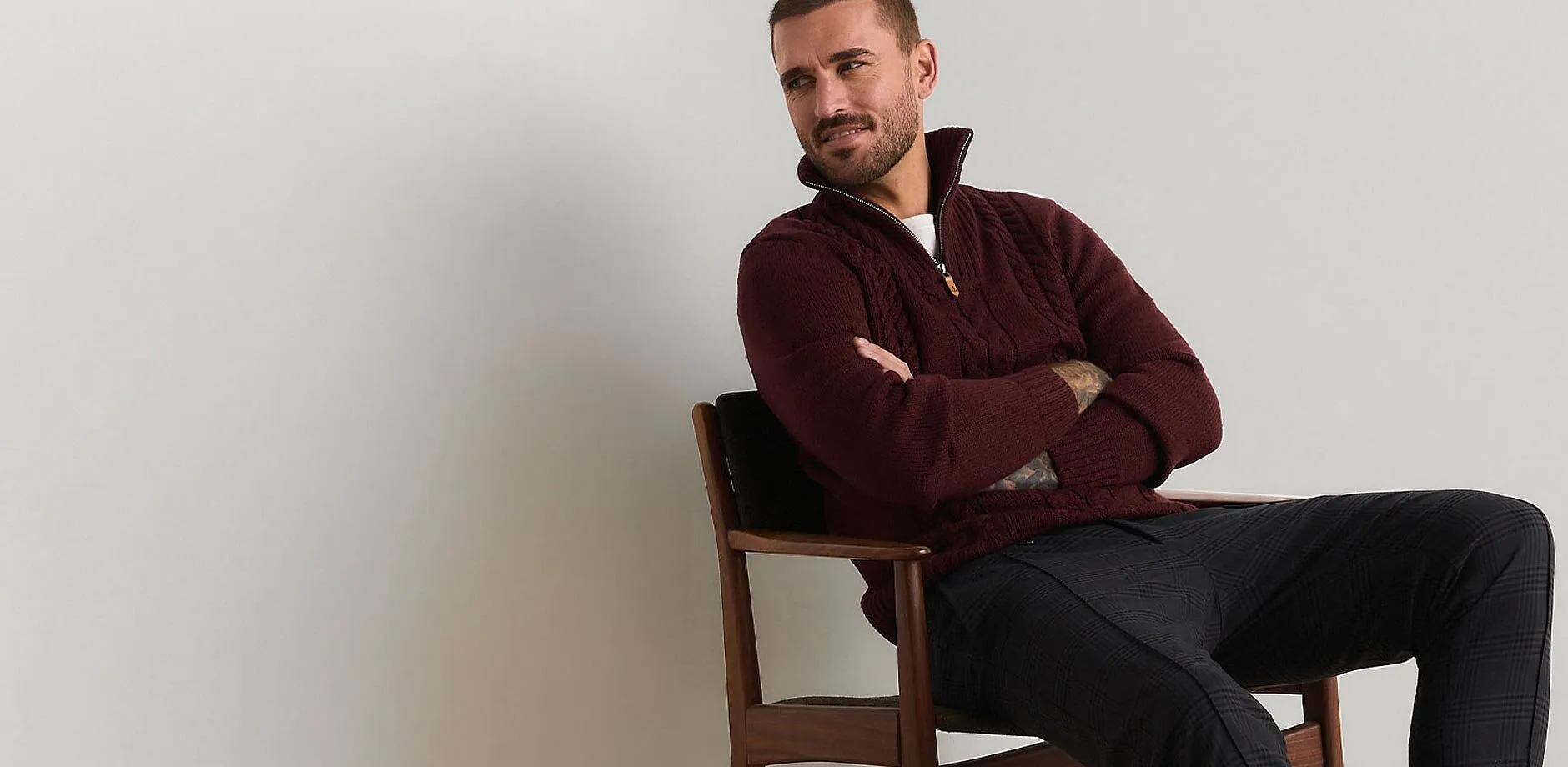 Dunkelroter Zopfstrickpullover mit Rei&szlig;verschluss und gemusterter Hose bilden ein stilvolles Outfit.