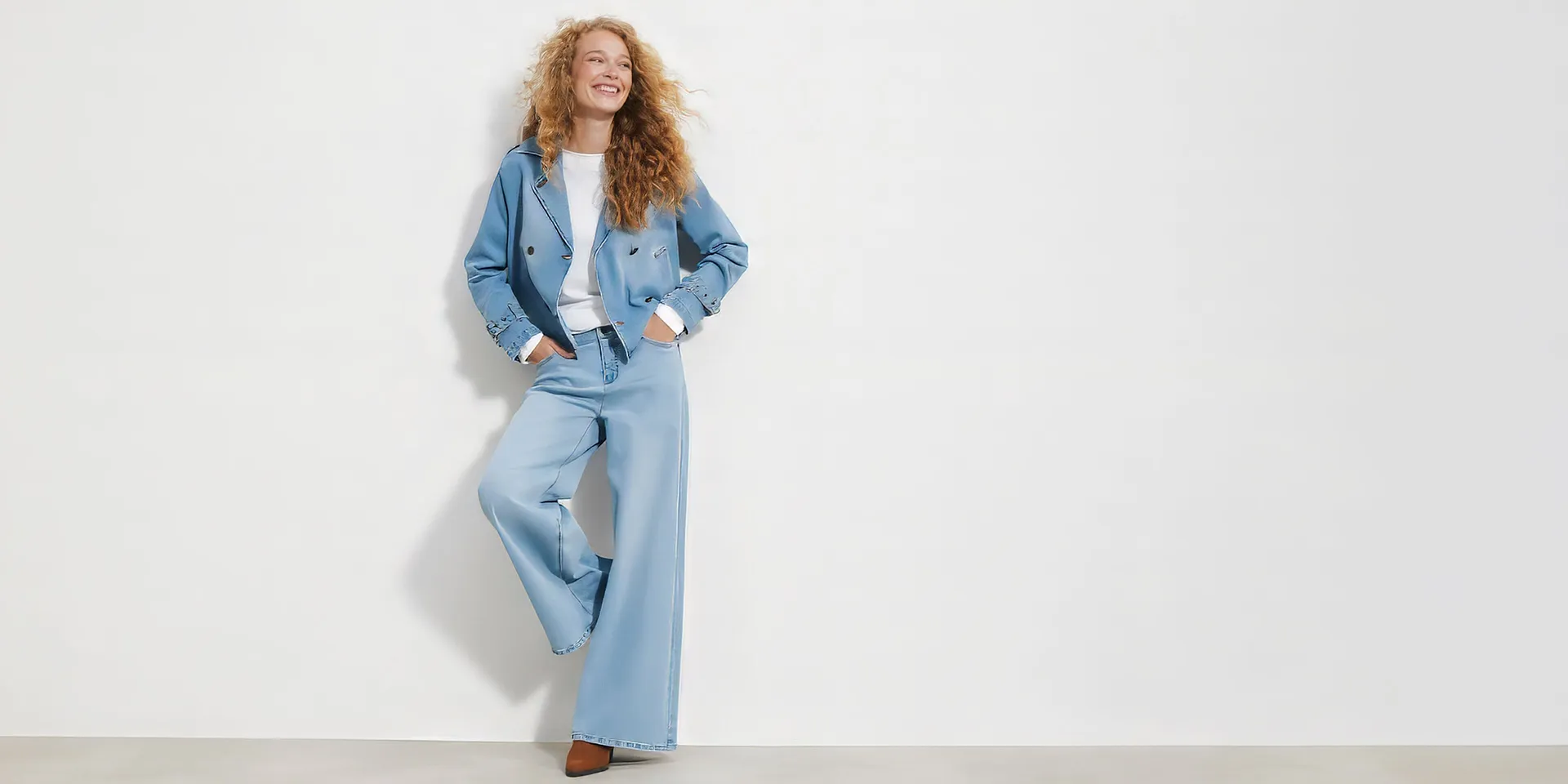 Veste courte en jean, pantalon large, T-shirt blanc et chaussures marron.