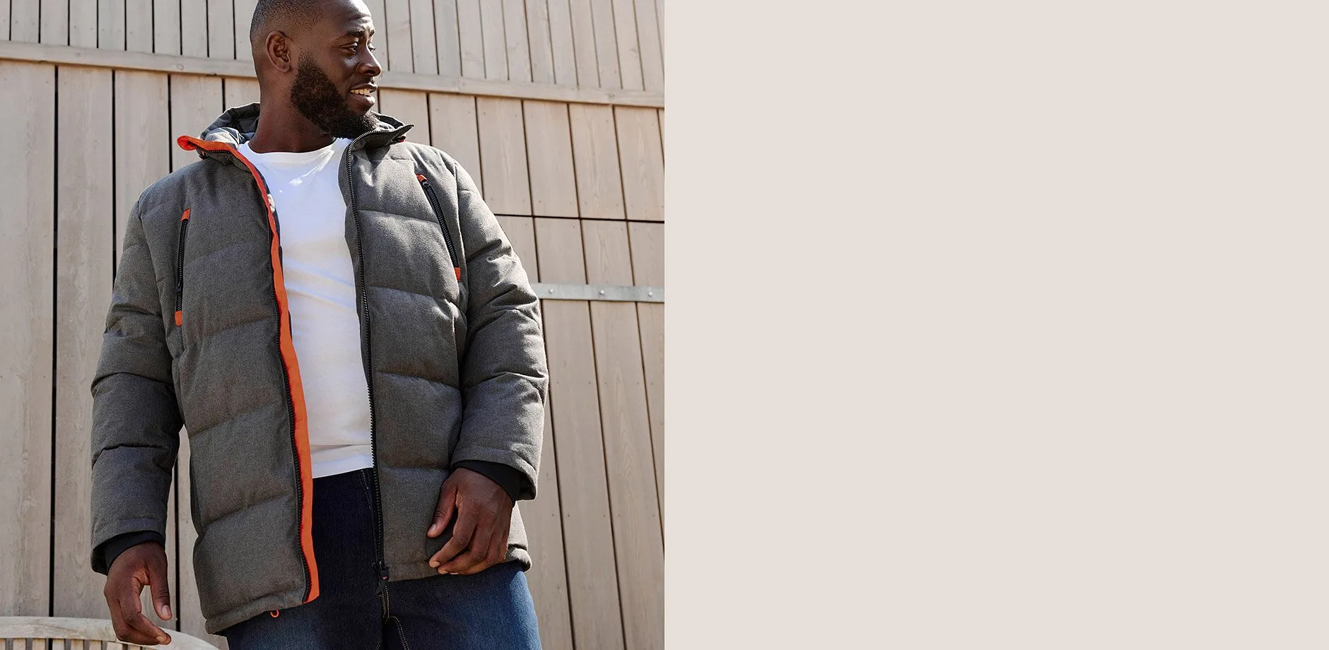 Graue Steppjacke mit orangen Akzenten, wei&szlig;es T-Shirt und blaue Jeans.