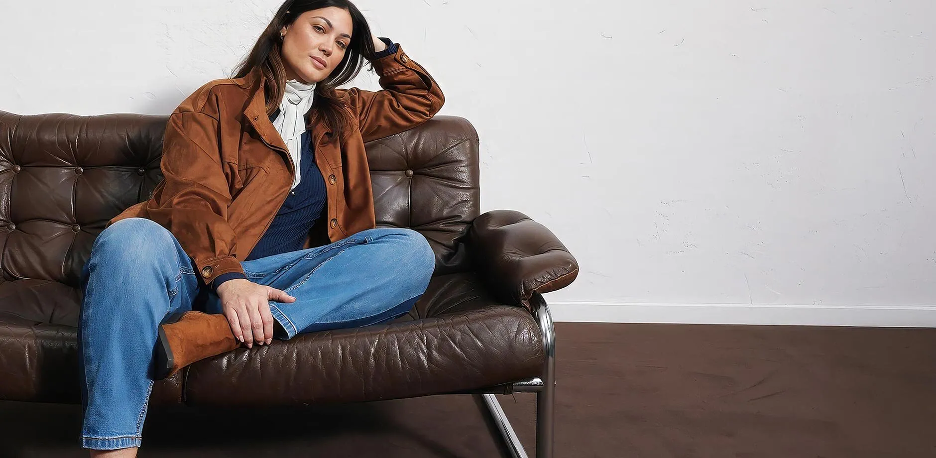 Veste en synth&eacute;tique marron, jean bleu, haut fonc&eacute;, &eacute;charpe claire et bottes.