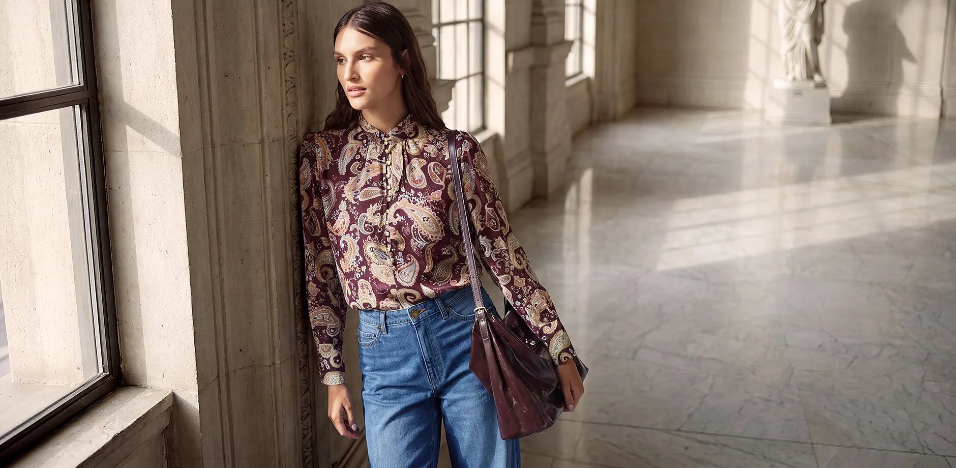 Stilvolle Paisley-Bluse mit Schleife, dazu weite Jeans und passende Ledertasche.