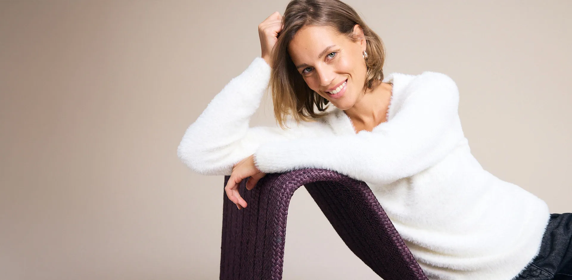 Wei&szlig;er, flauschiger Pullover und dunkle Hose betonen den entspannten Stil.