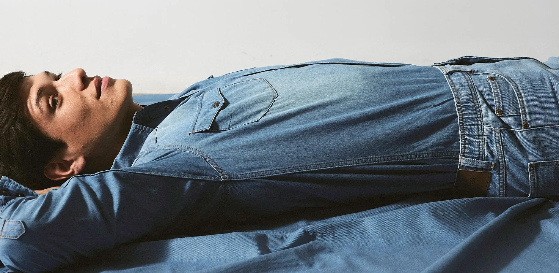 Jean bleu pr&egrave;s corps avec coutures contrast&eacute;es et un &eacute;cusson marron.
