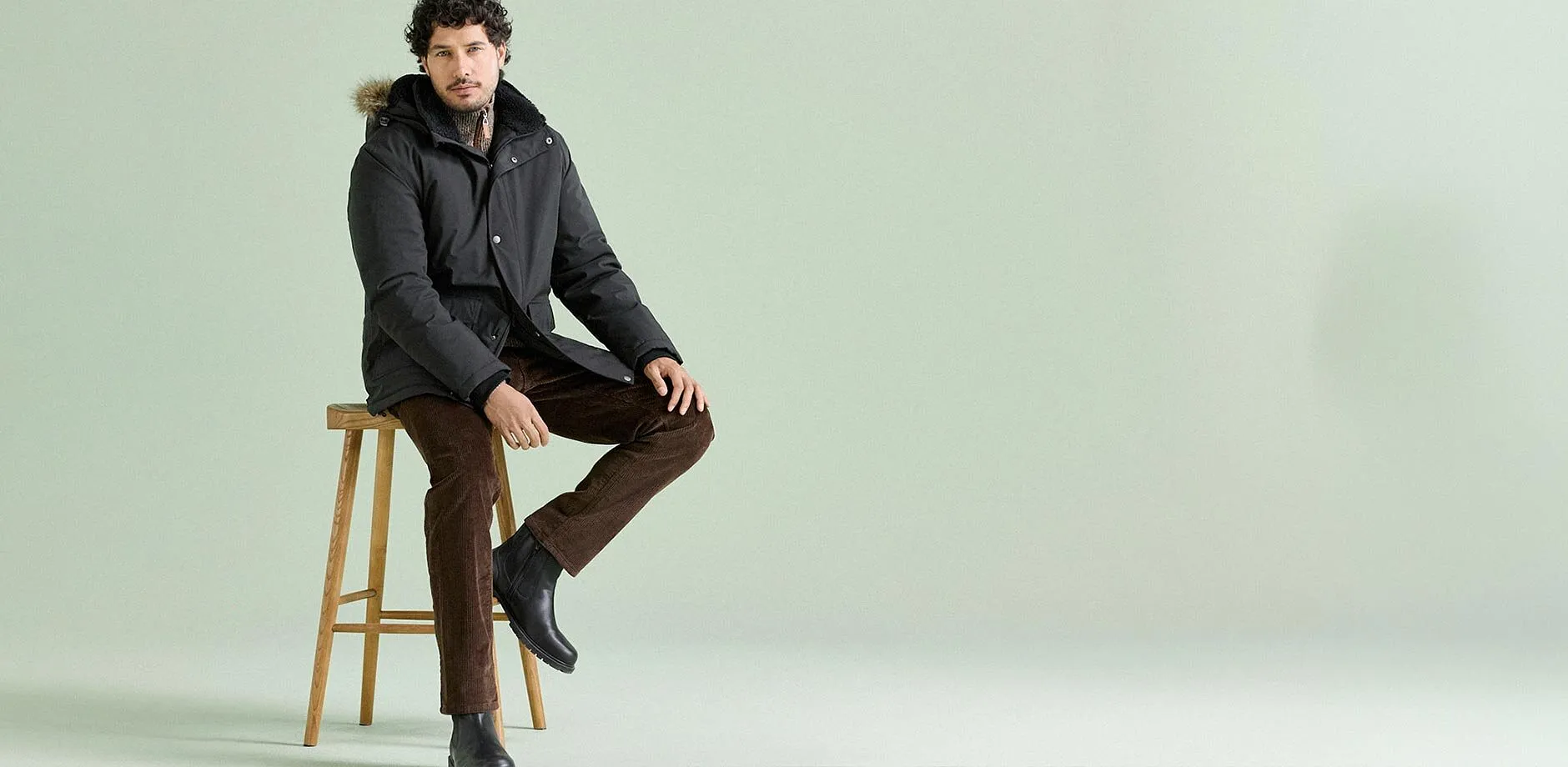 Tenue hivernale avec parka chaude, pantalon en velours c&ocirc;tel&eacute; marron et bottes noires.