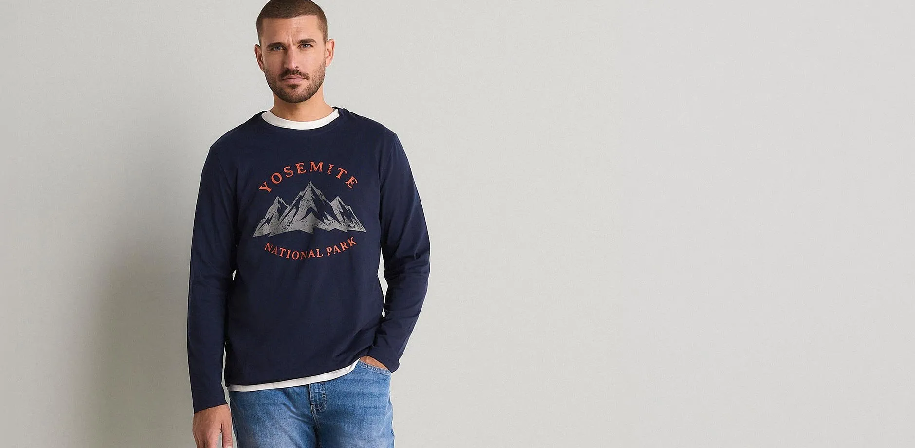 Un homme v&ecirc;tu d'un jean et d'un T-shirt bleu fonc&eacute; &agrave; manches longues avec imprim&eacute; Yosemite National Park.