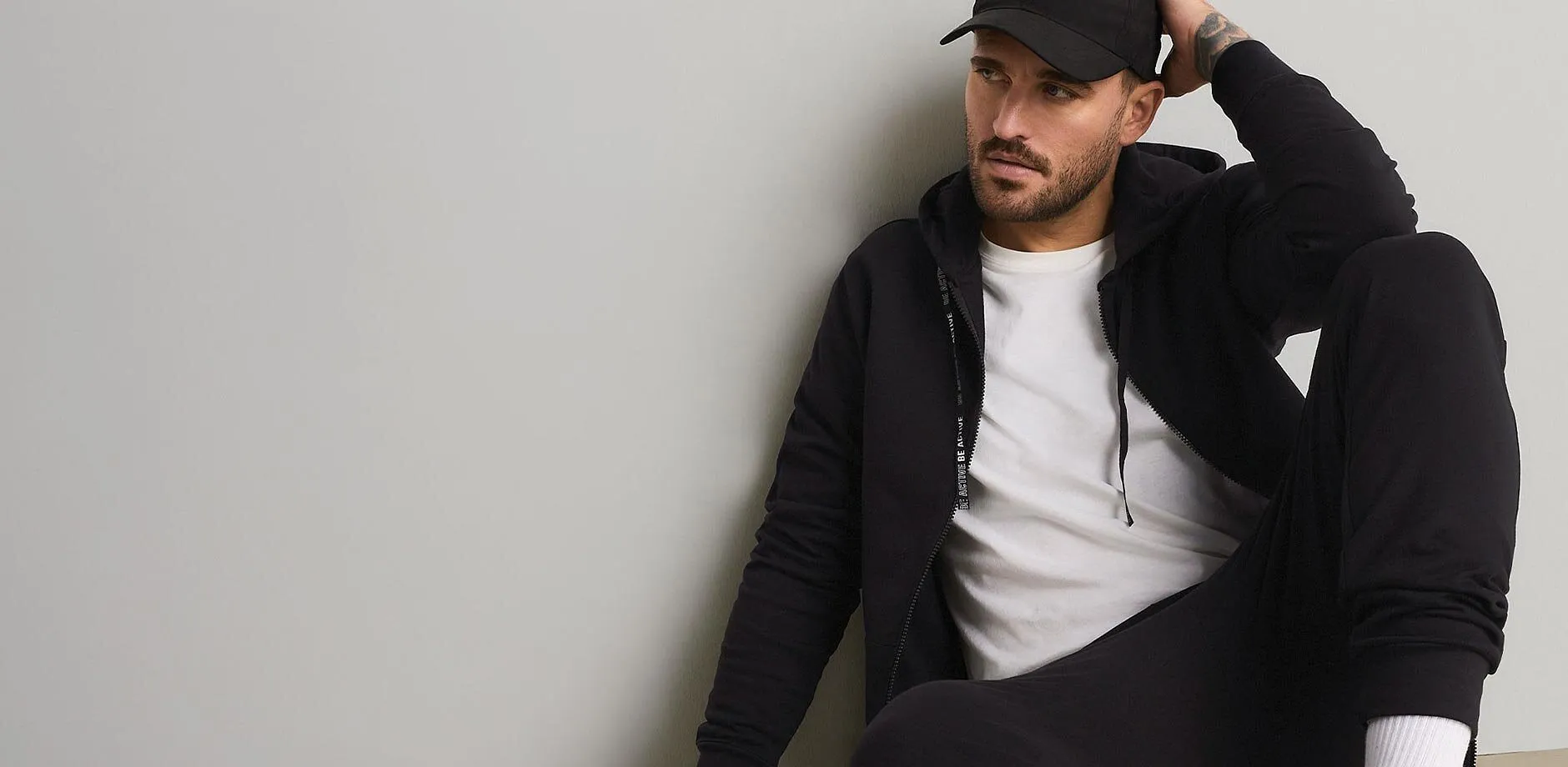 Casquette noire, sweat &agrave; capuche, T-shirt blanc et pantalon de jogging confortable pour un look d&eacute;contract&eacute;.