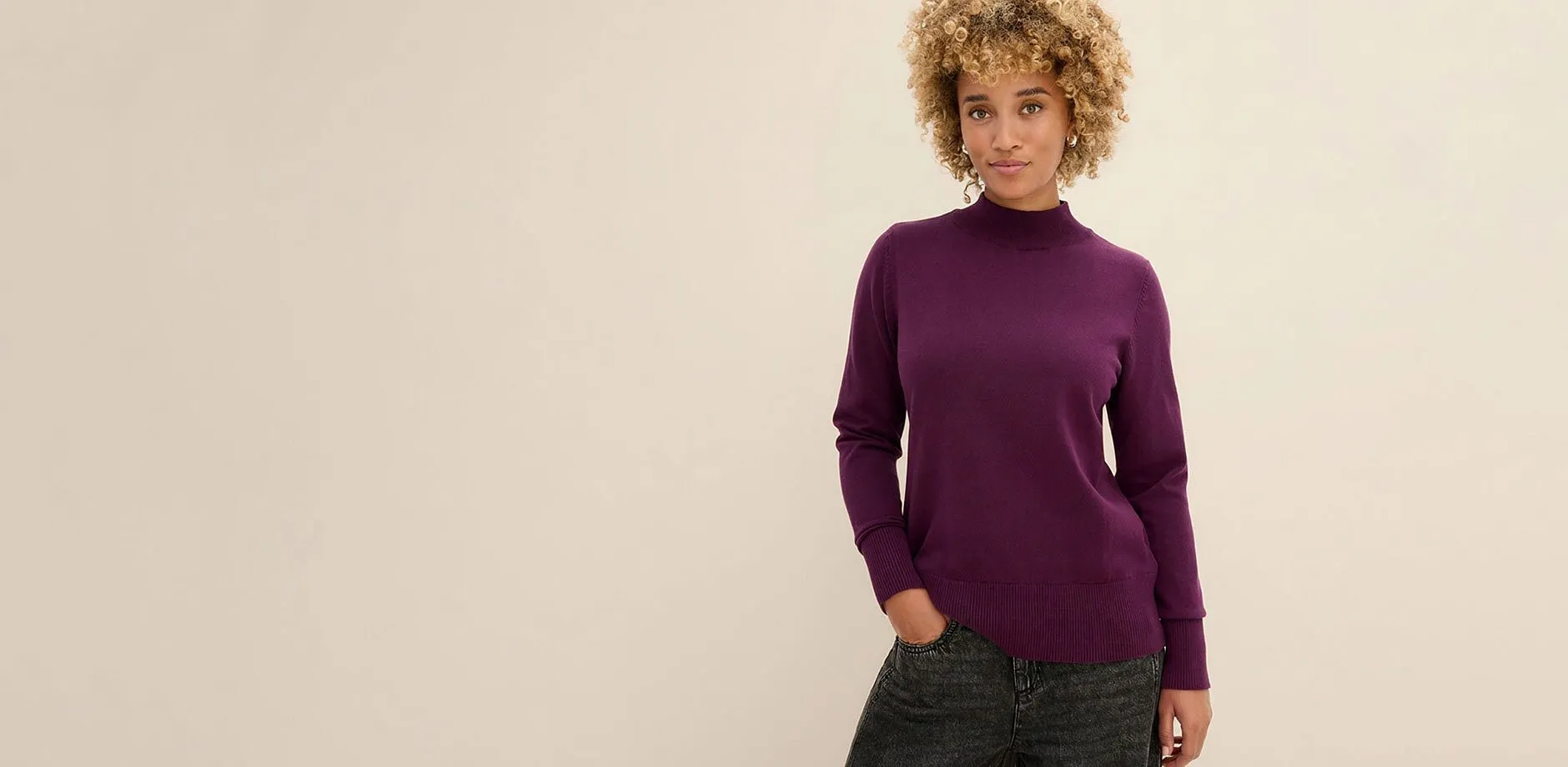 Femme v&ecirc;tue d'un pull violet mode &agrave; col montant et d'un jean noir.