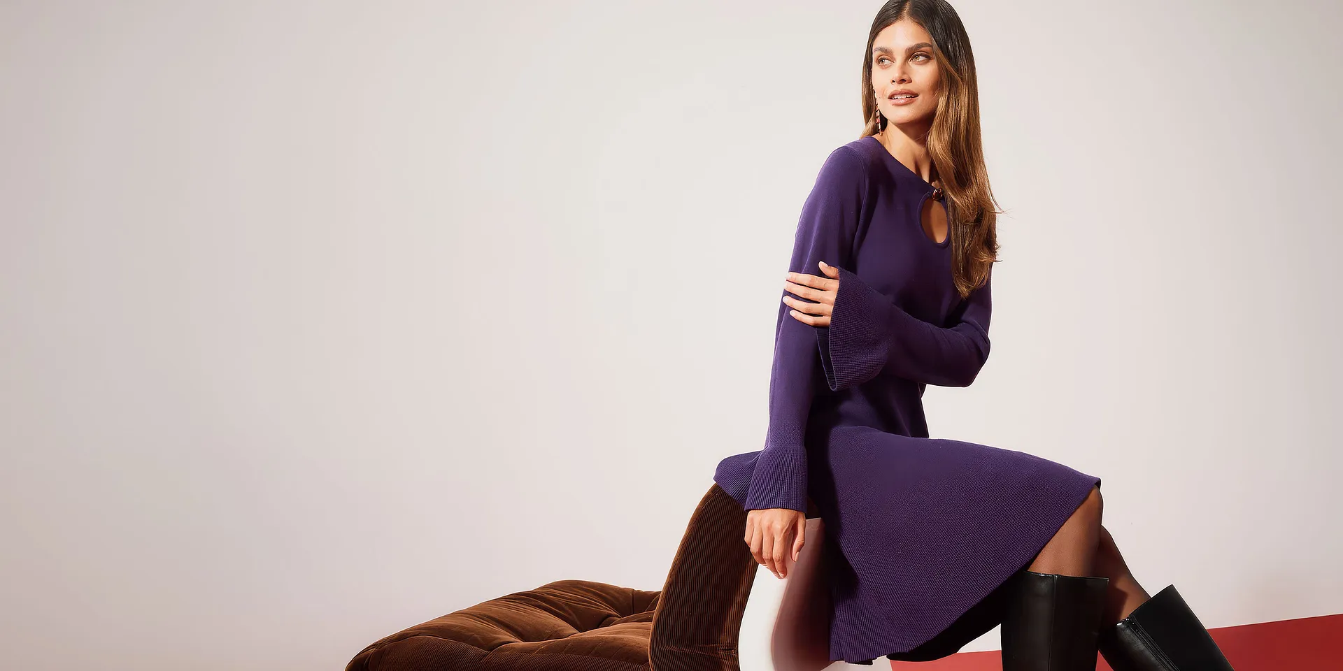 Elegantes violettes Strickkleid mit weiten &Auml;rmeln, kombiniert mit hohen schwarzen Stiefeln.