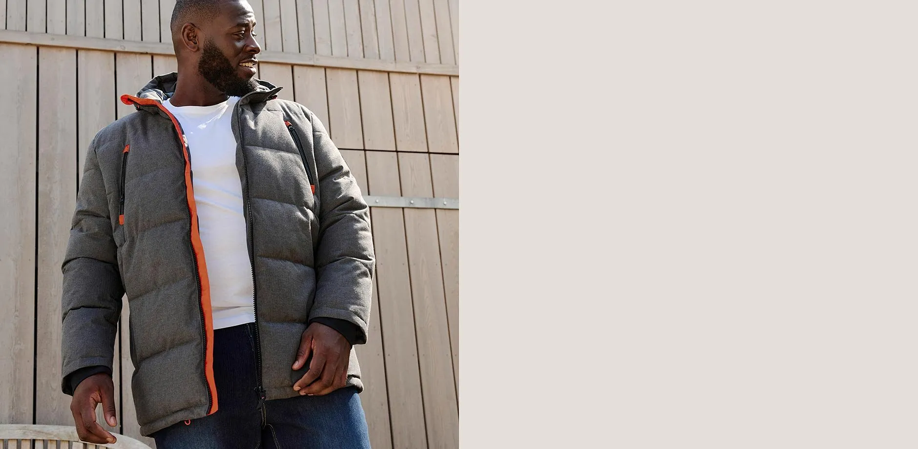 Graue Steppjacke mit orangen Akzenten, wei&szlig;es T-Shirt und blaue Jeans.