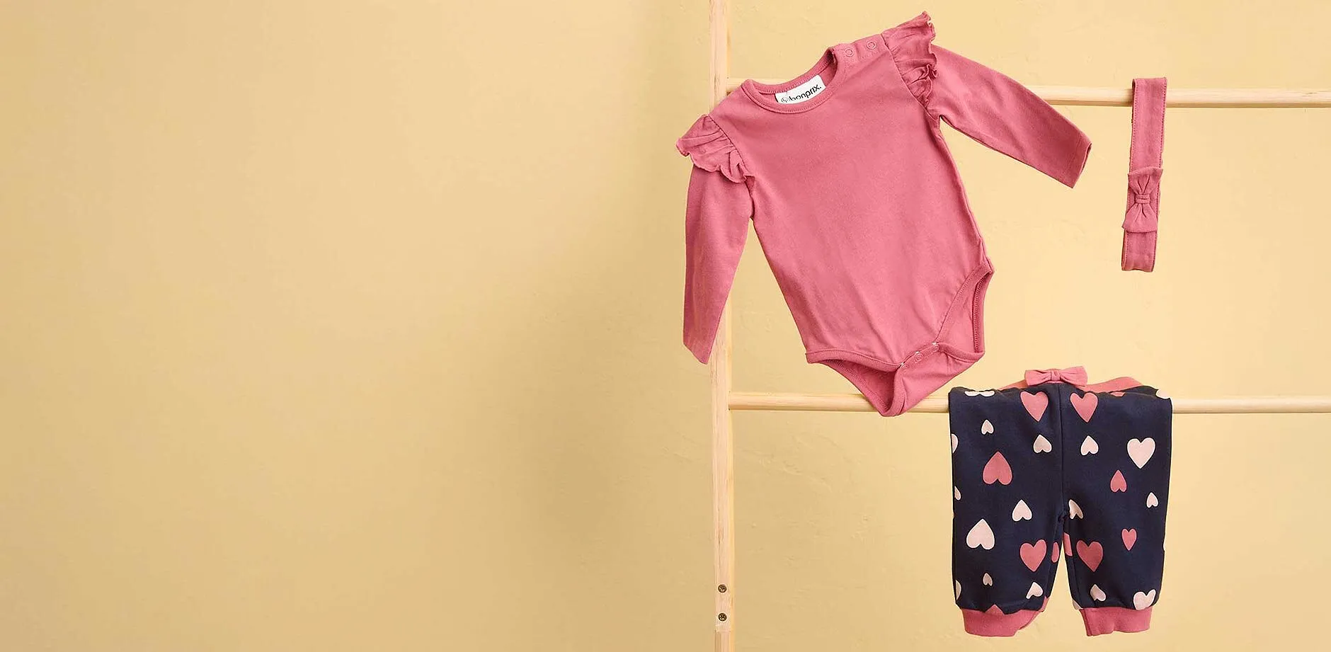 S&uuml;&szlig;es Babyset: Rosa Body und dunkelblaue Hose mit Herz-Muster.