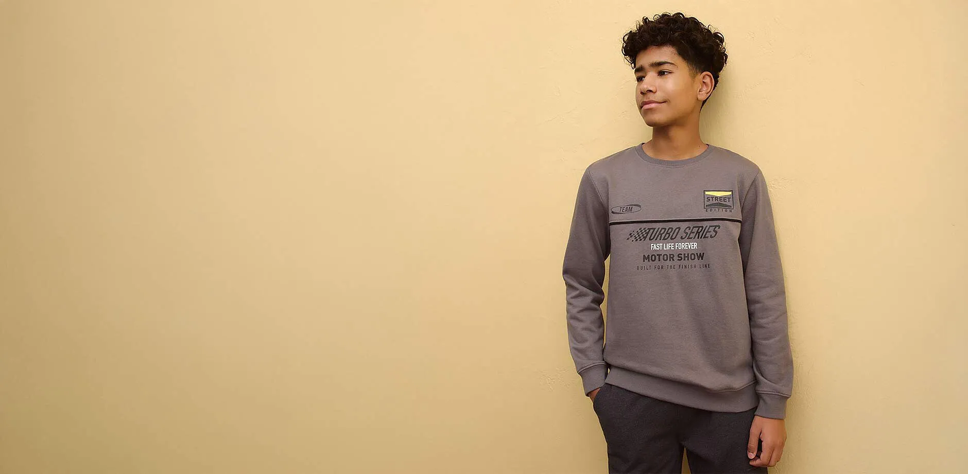 Pull gris avec inscription, associ&eacute; &agrave; un pantalon fonc&eacute;.