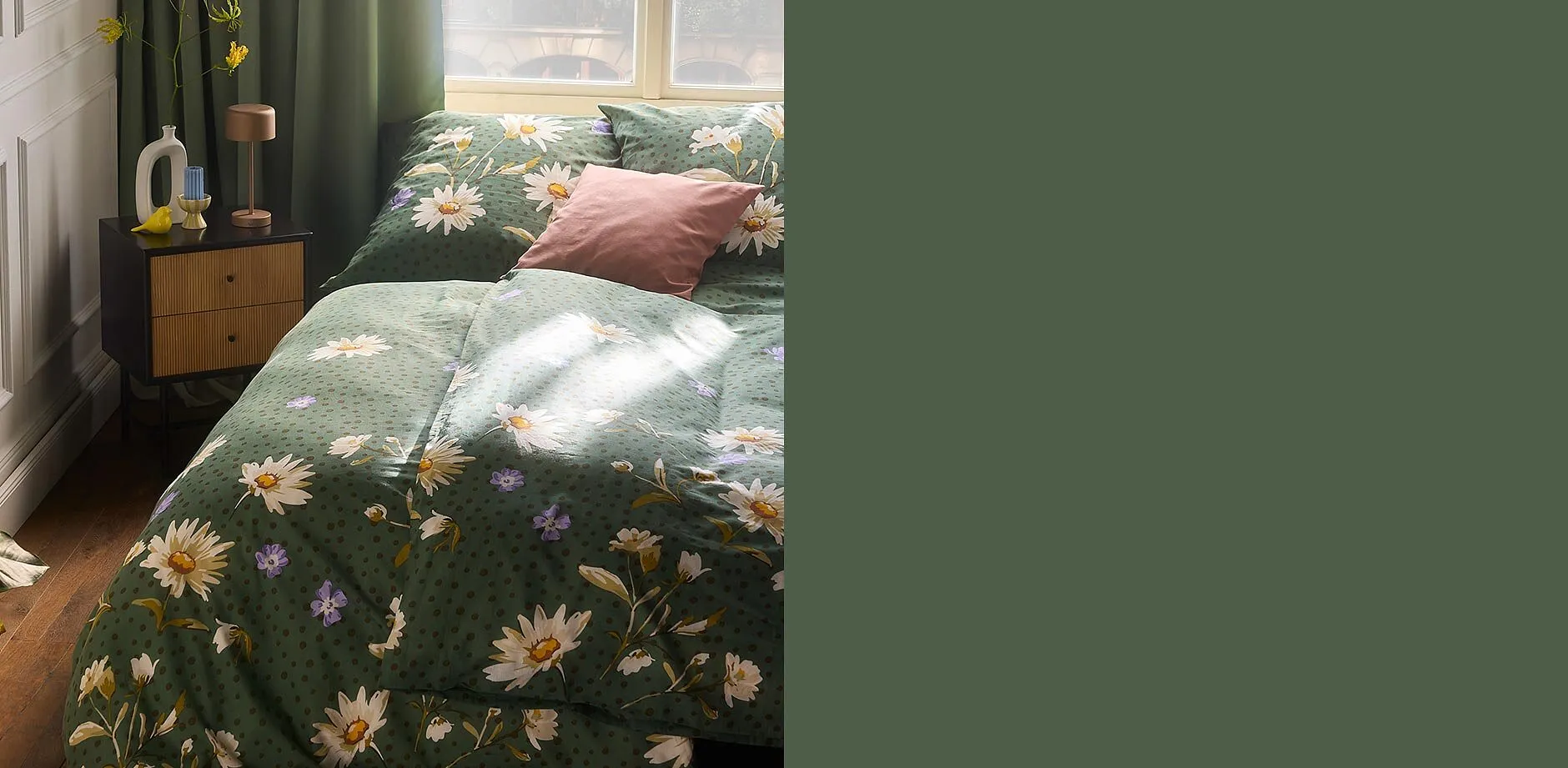 Blumige Bettw&auml;sche in Gr&uuml;n schm&uuml;ckt das Bett, erg&auml;nzt durch passende Kissen.