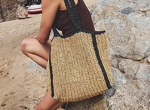 Sommerliche Strandtasche aus Stroh mit schwarzen Akzenten.