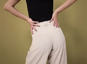 Eleganter Kontrast: Schwarzes, ärmelloses Oberteil trifft auf weite, cremefarbene Hose mit hohem Bund.