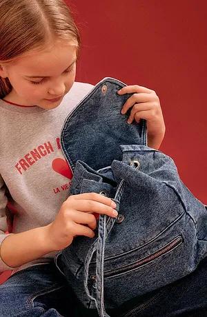 Sweat-shirt gris avec inscription rouge et sac à dos en jean bleu. Un look décontracté au quotidien pour les jeunes.